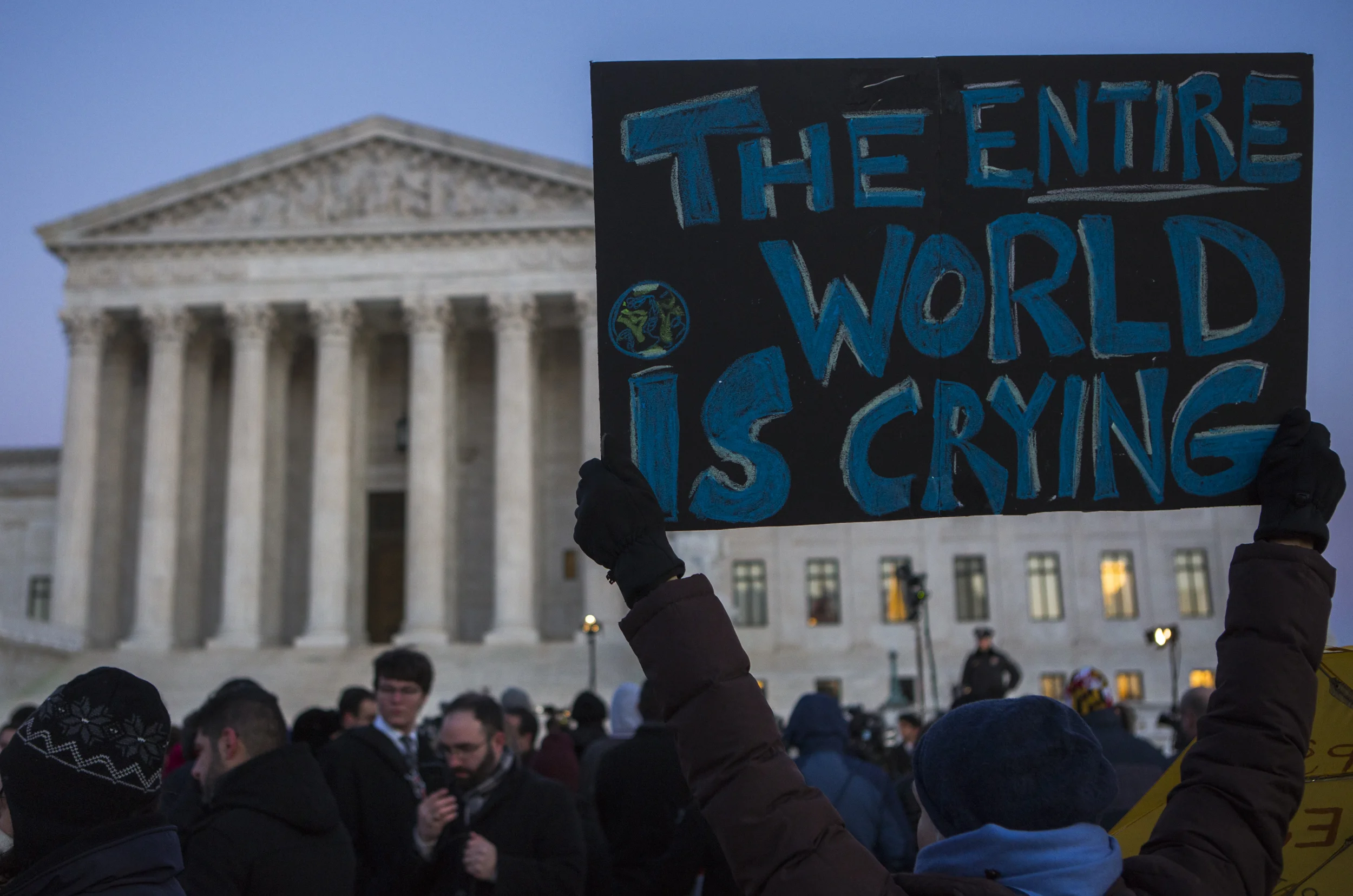 A protester holds up a sign at the steps of the Supreme Court before the start of the rally organized by democratic lawmakers opposing President Trump's executive order banning travel and immigration to select countries.