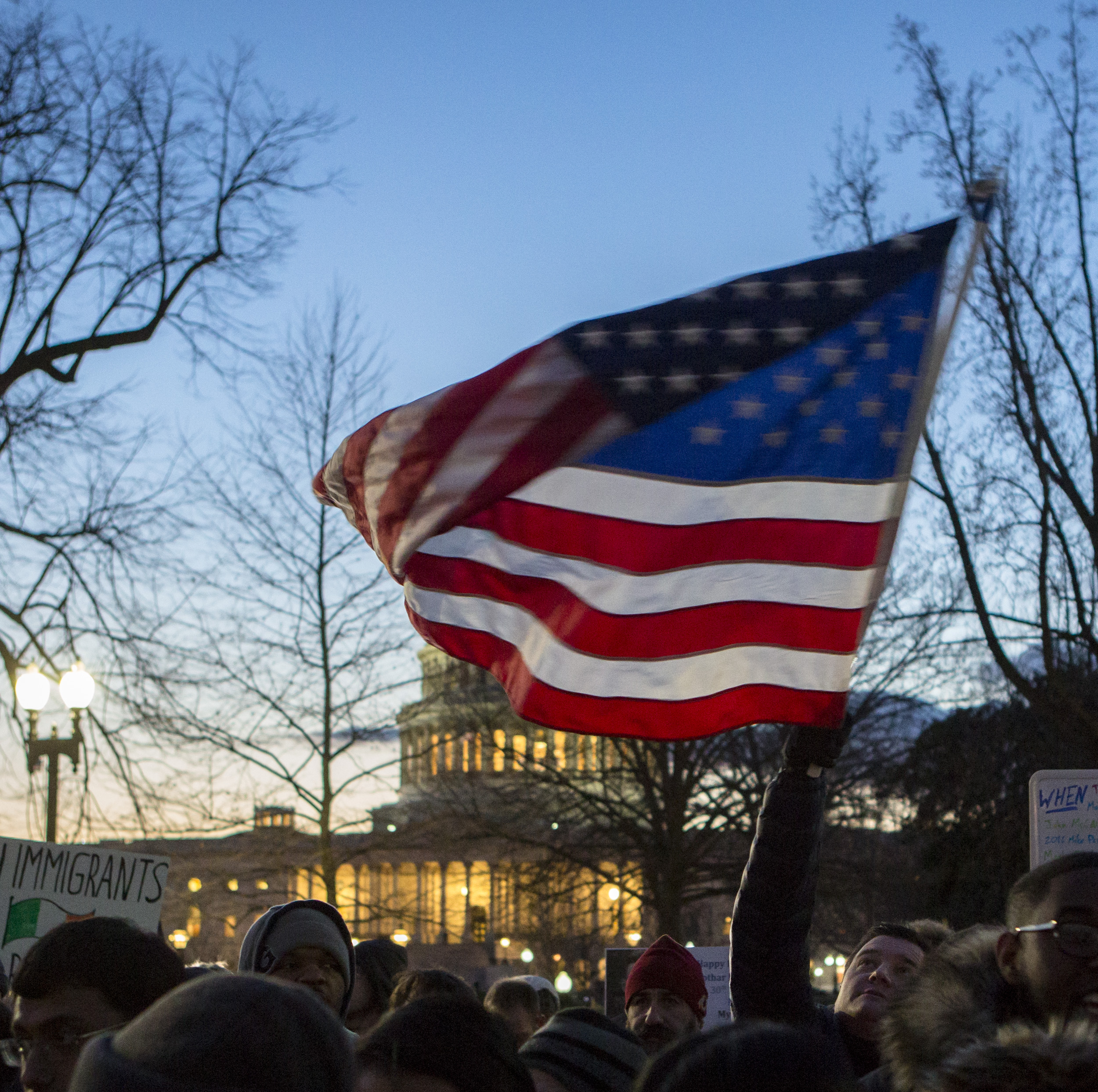 A rally participant waves an American flag as the crowd chants anti-Trump and anti hate slogans.