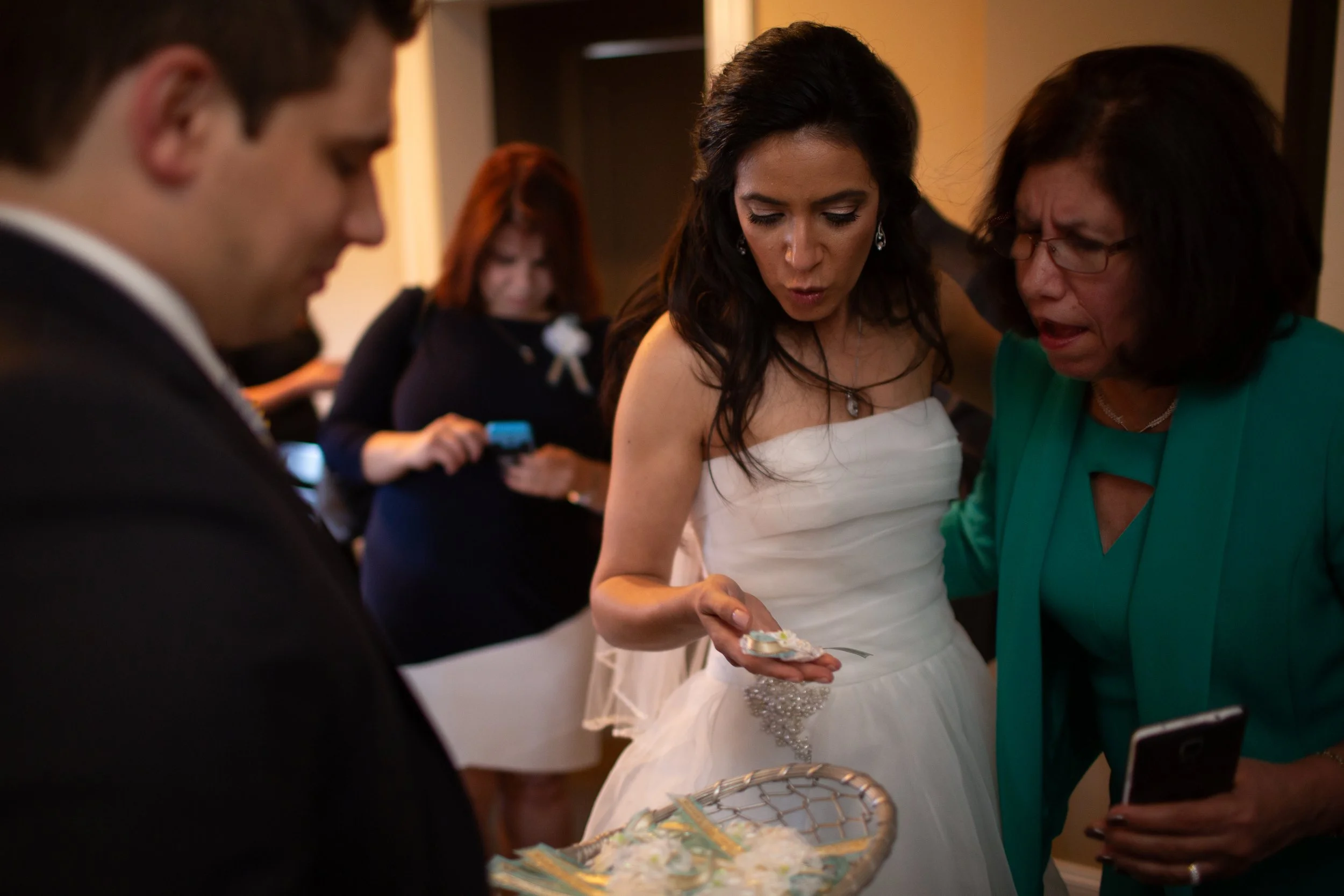 Woman in a white dress and woman in a green dress cutting a cake at a celebration.