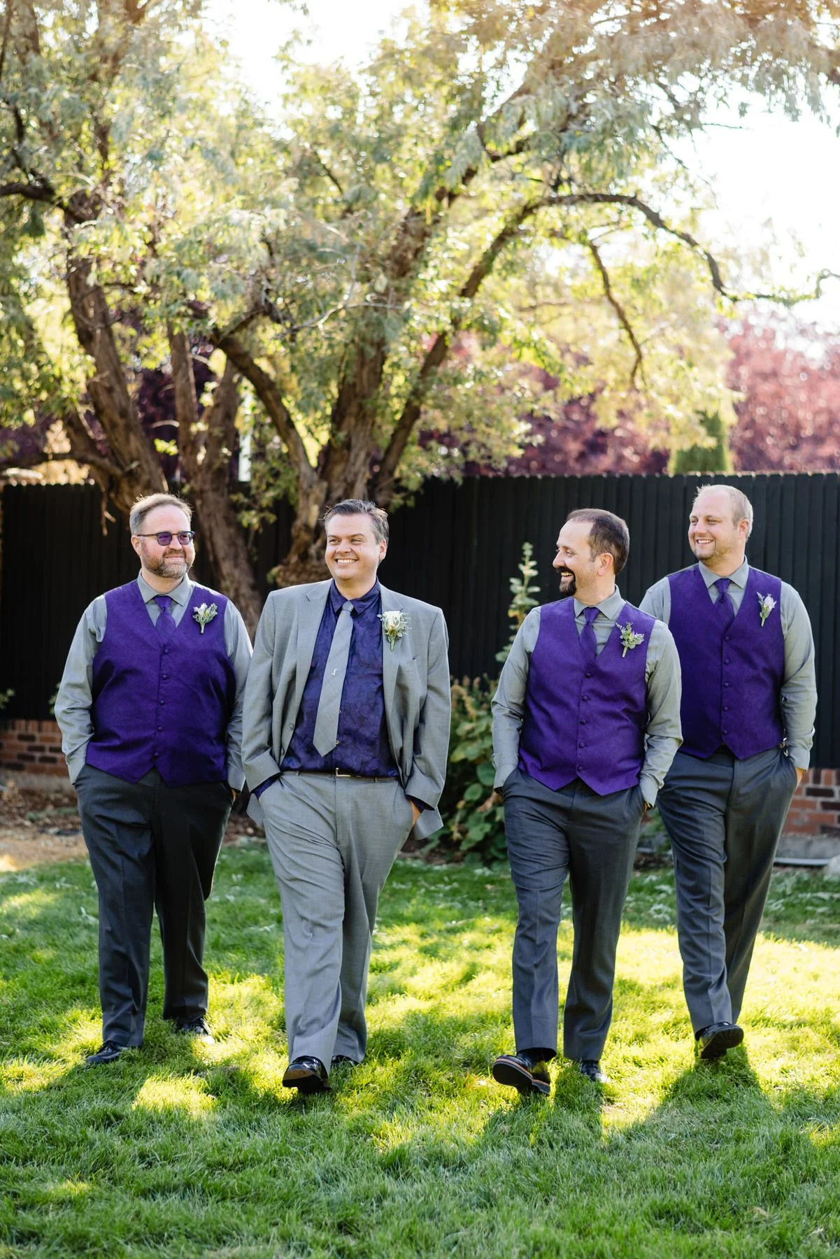 a groom and his groomsmen in purple pose for their wedding party photos