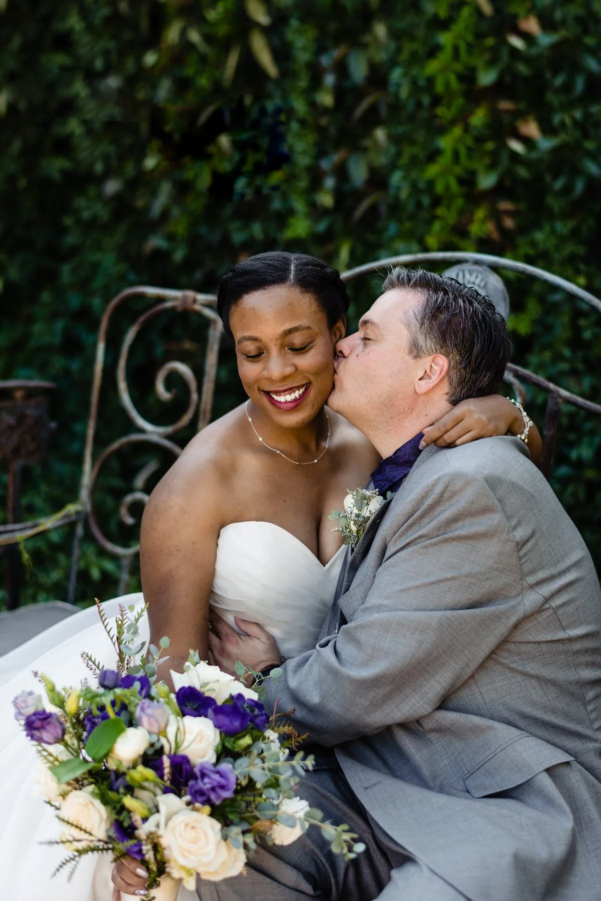 bride and groom share a kiss on a bench at the Lionsgate Event Center