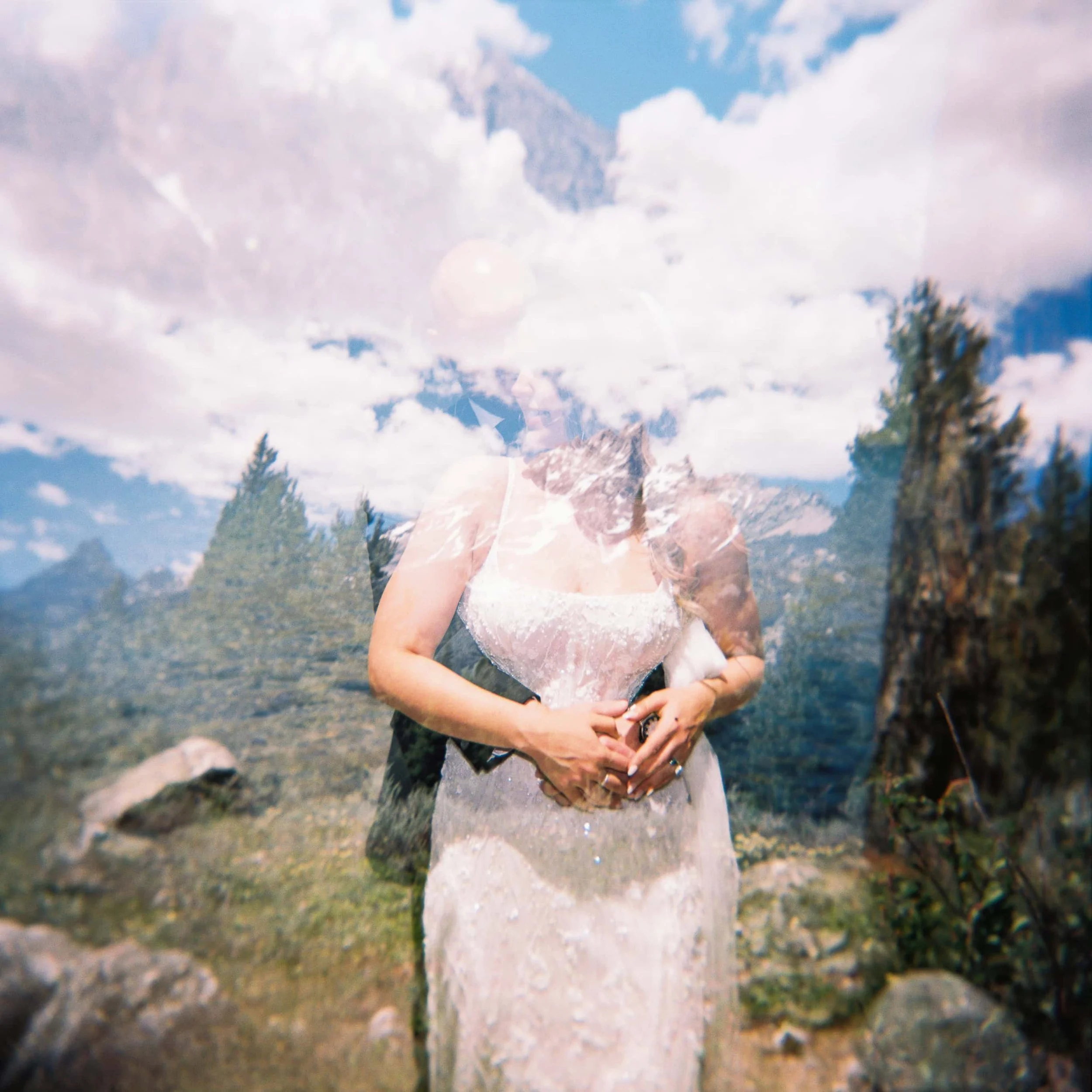 a double exposure film image of a couple in front of the mountains
