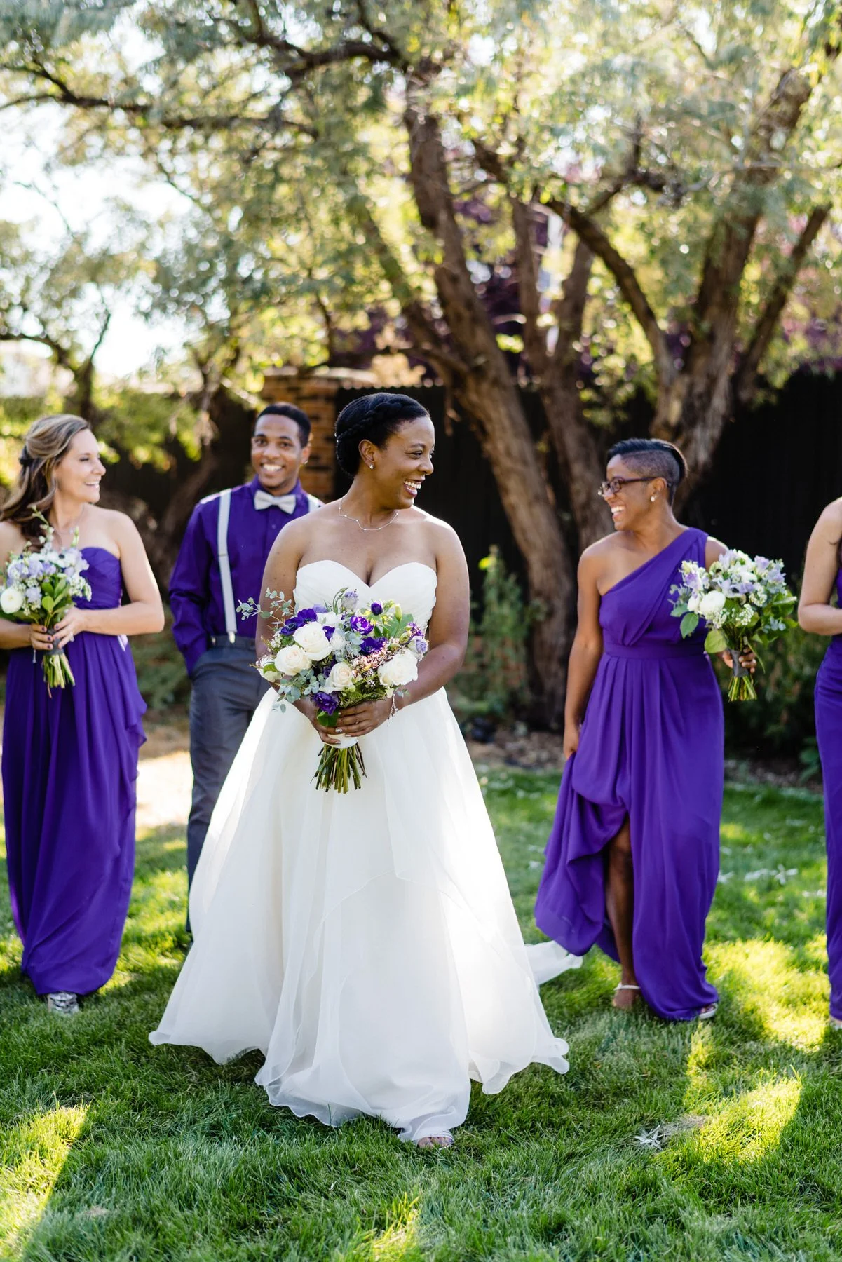 a bride and her wedding party in purple pose for their wedding party photos