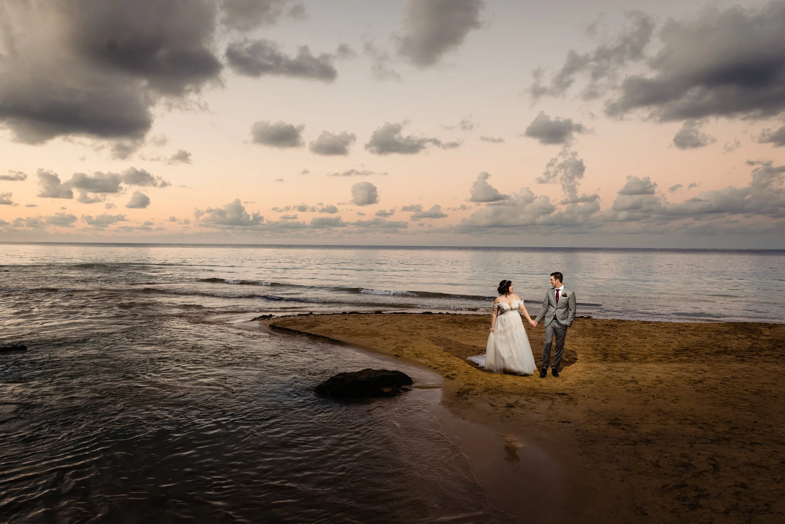 man and woman walk on beach at sunset