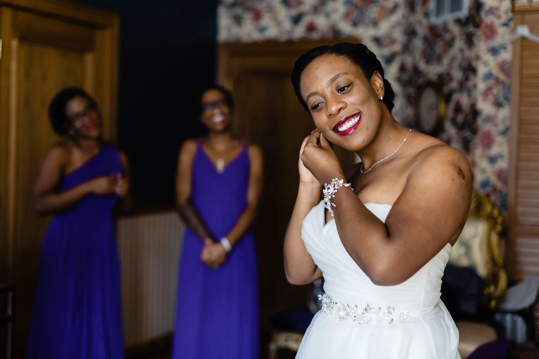 a bride puts on her earrings while her wedding party watches at Lionsgate Event Center in Lafayette, Co