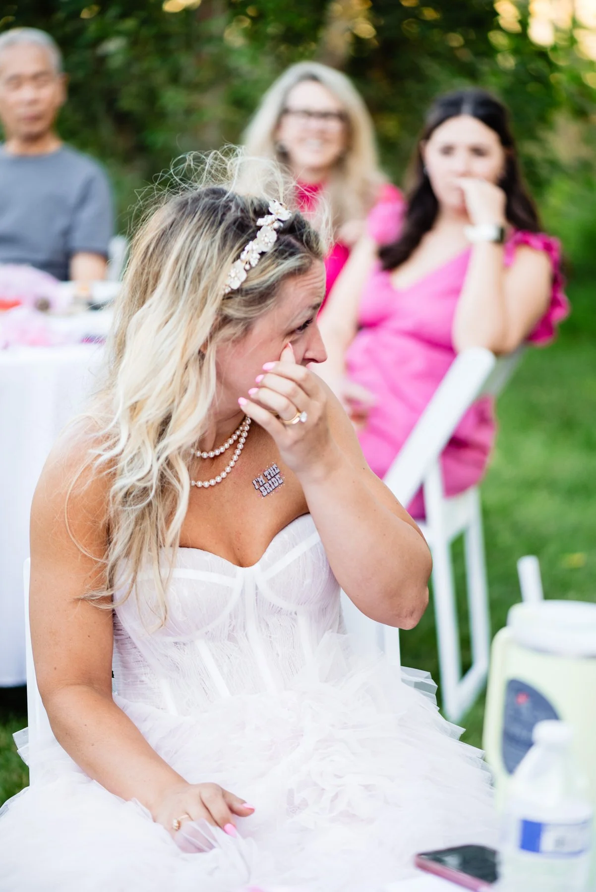 a bride at a wedding wipes a tear during a wedding speech
