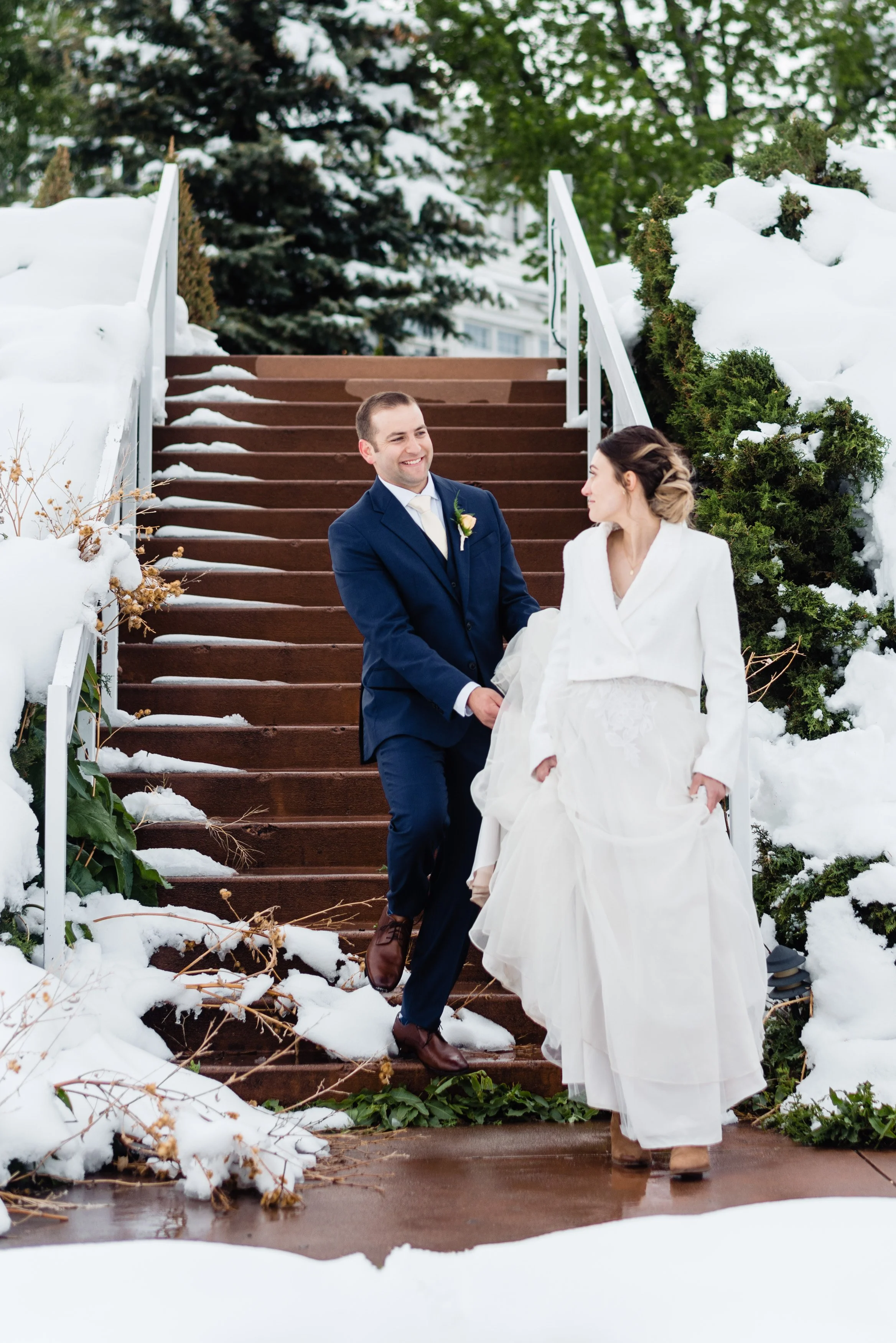 A bride and groom walking down stairs in the snow