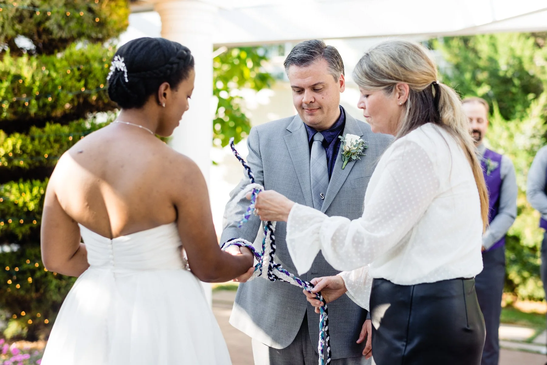 officiant helps bride and groom tie a knot on their wedding day