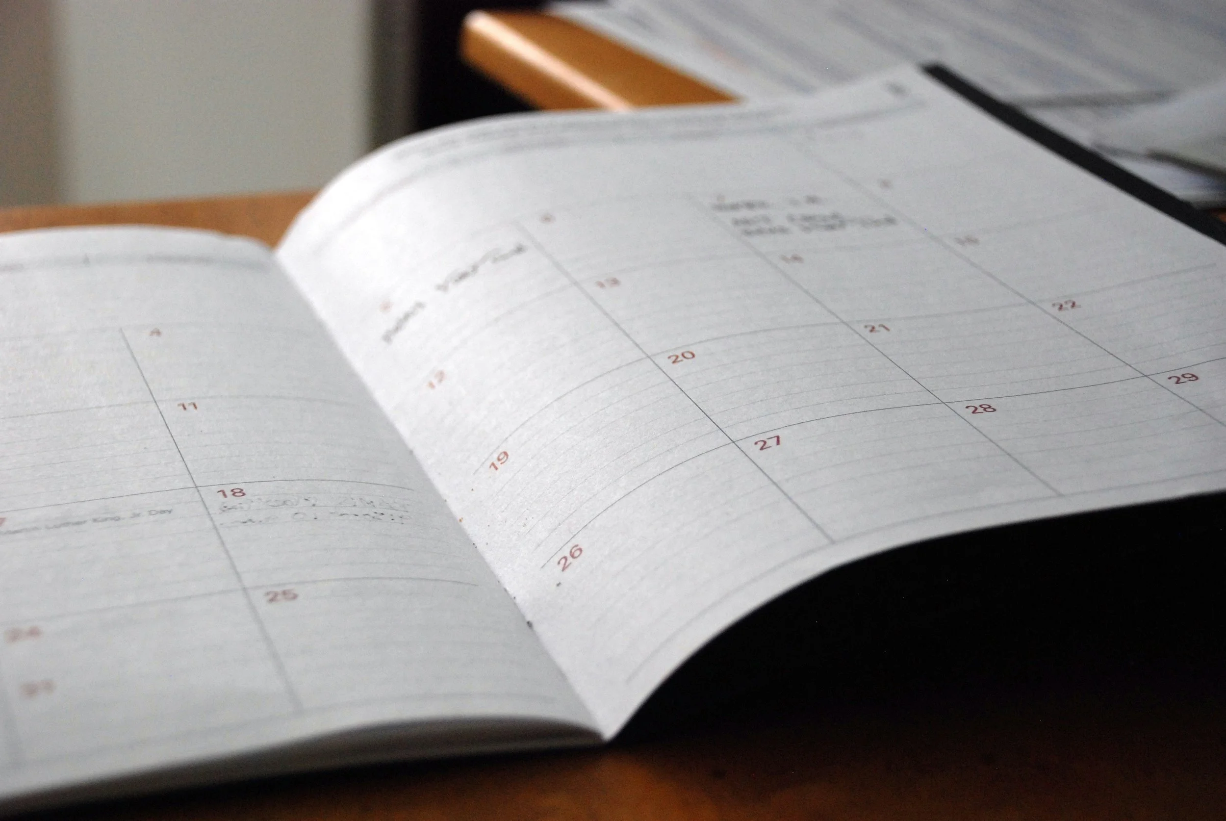 Open planner or calendar on a wooden table with visible dates and notes.