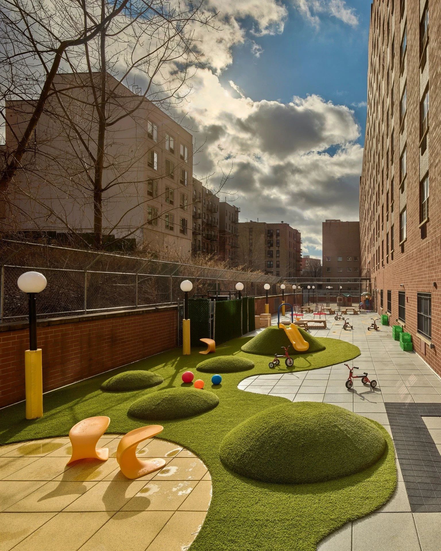 Terrace time! Our terrace design at La Escuela Comunitaria del Bronx offers diverse play and learning zones for various ages and group sizes. There is a protected play area for younger children, differently-sized turf hills, a built-in slide, custom 