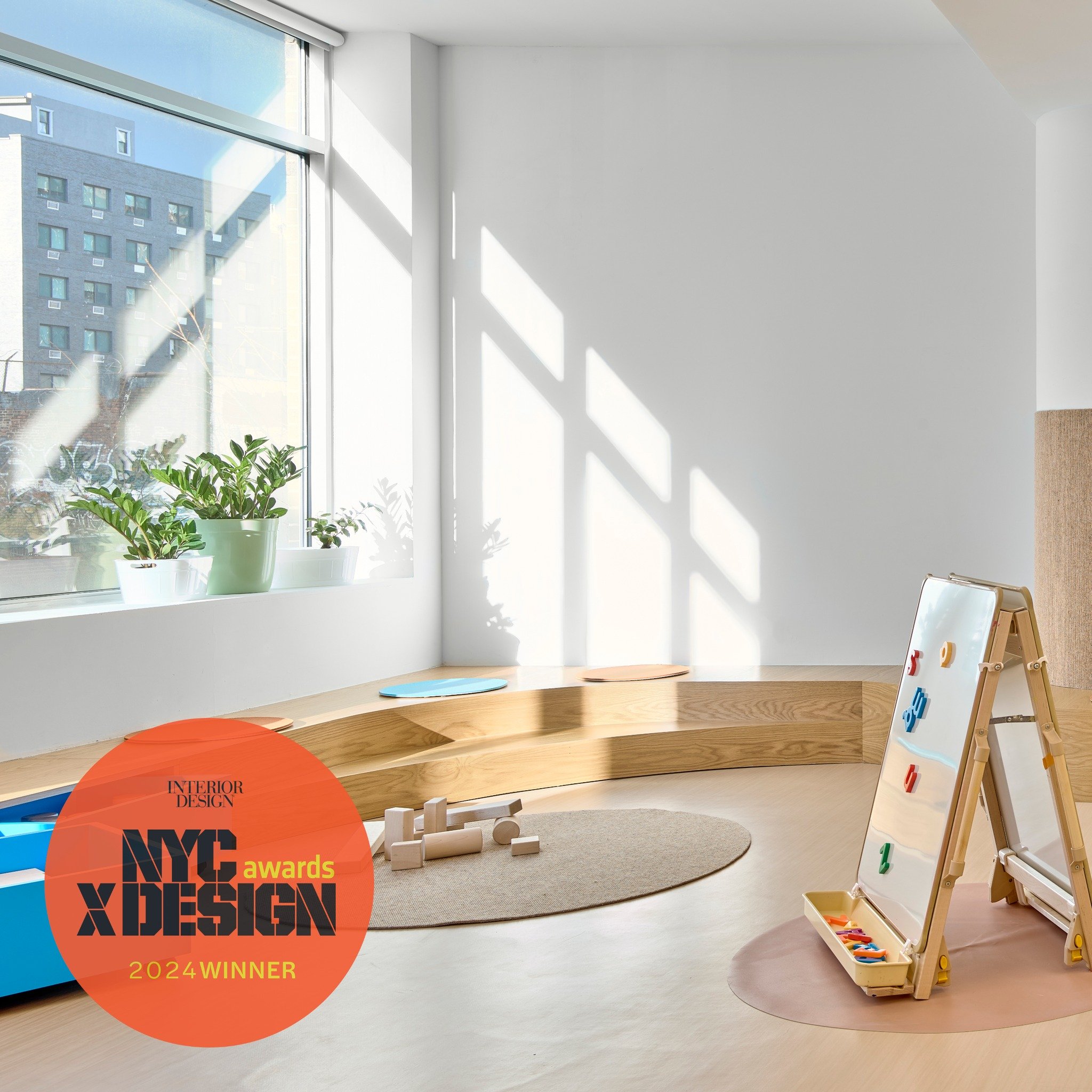 Bright beginnings with books! The multipurpose room in our award-winning La Escuela Comunitaria del Bronx is illuminated by daylight pouring through large windows. The custom wood seat-steps that we designed are a perfect place to read picture books.