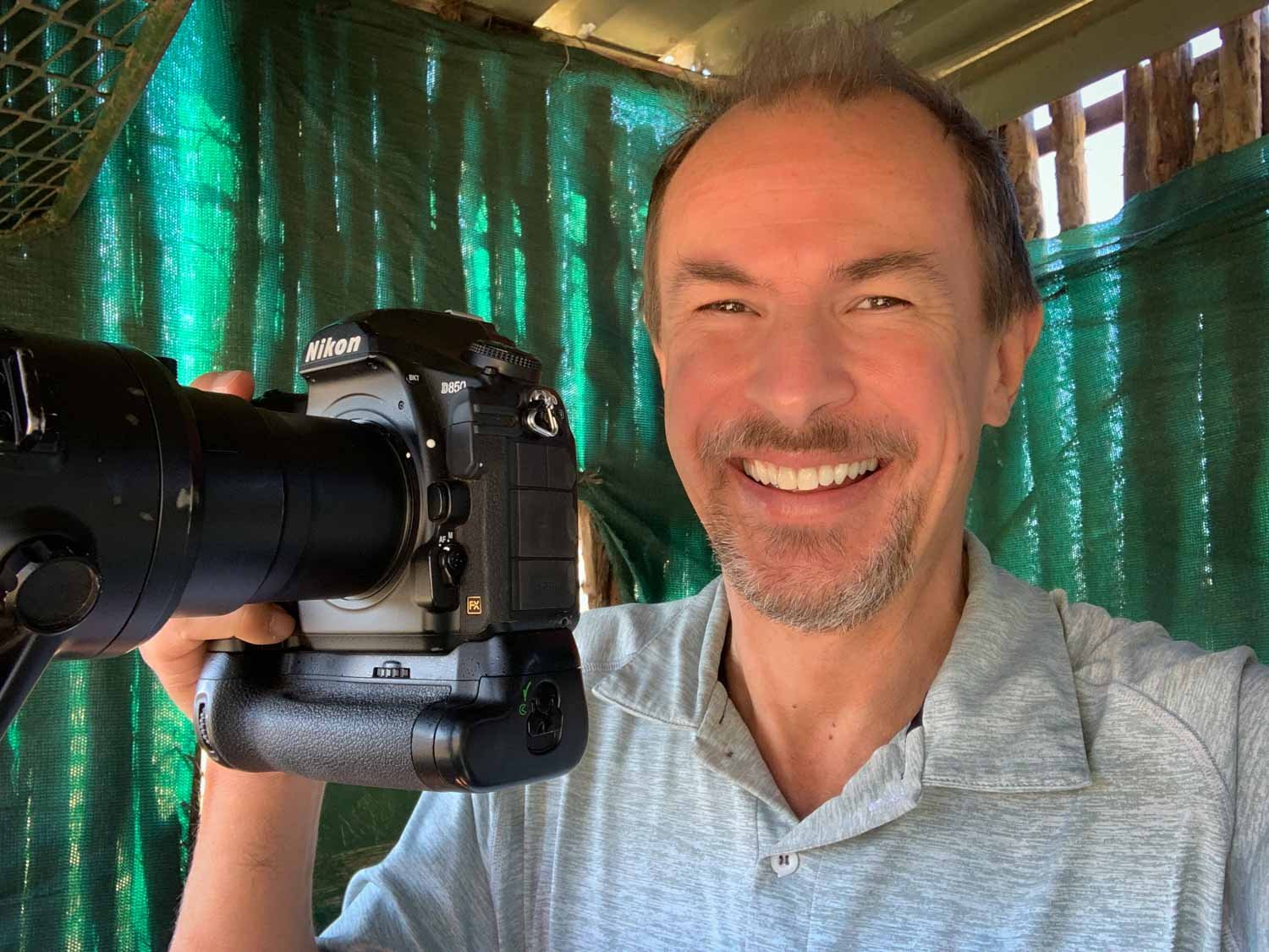 Smiling man sits in hide with camera.jpg