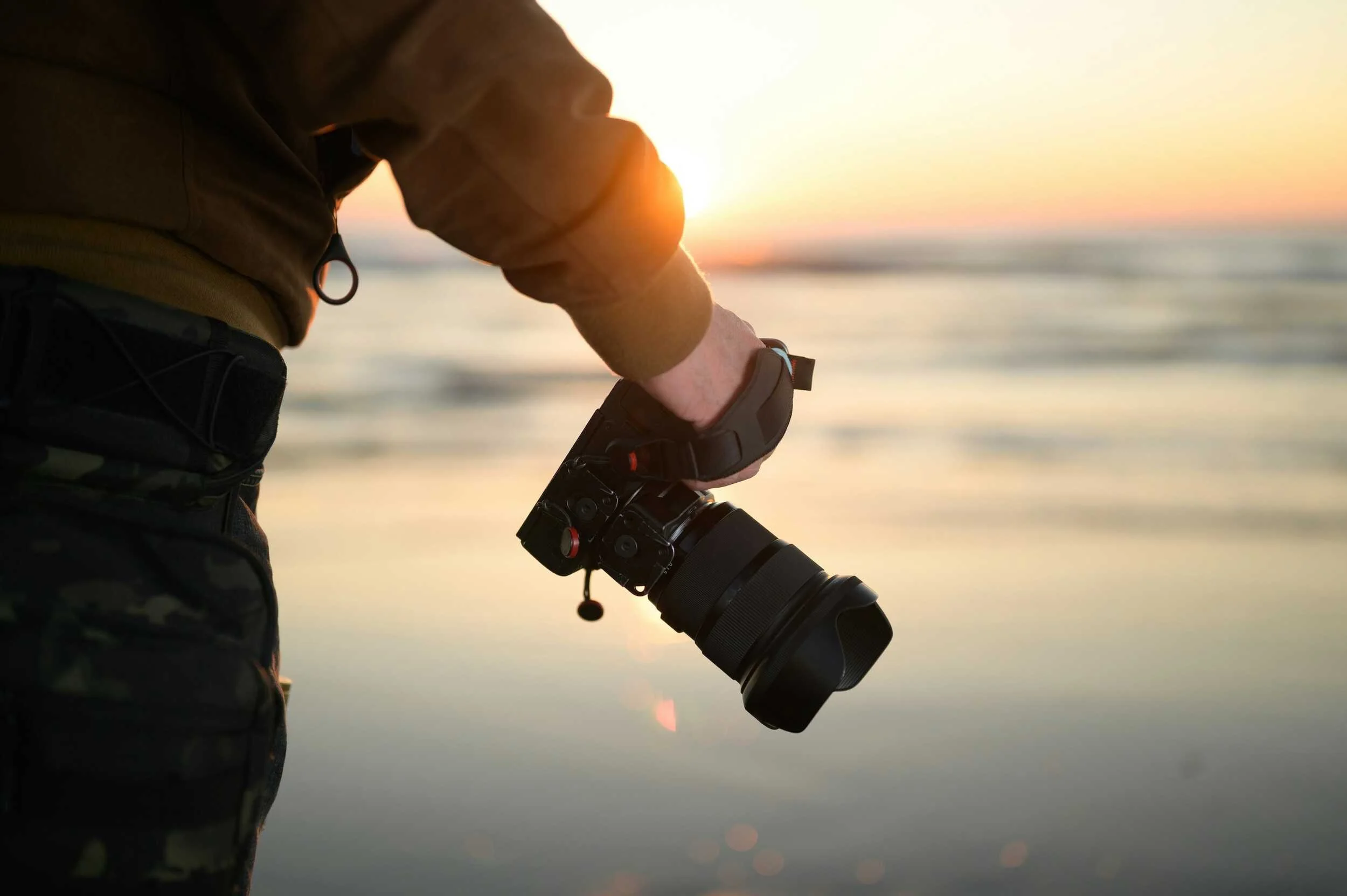 Man carries camera on mountain at sunset