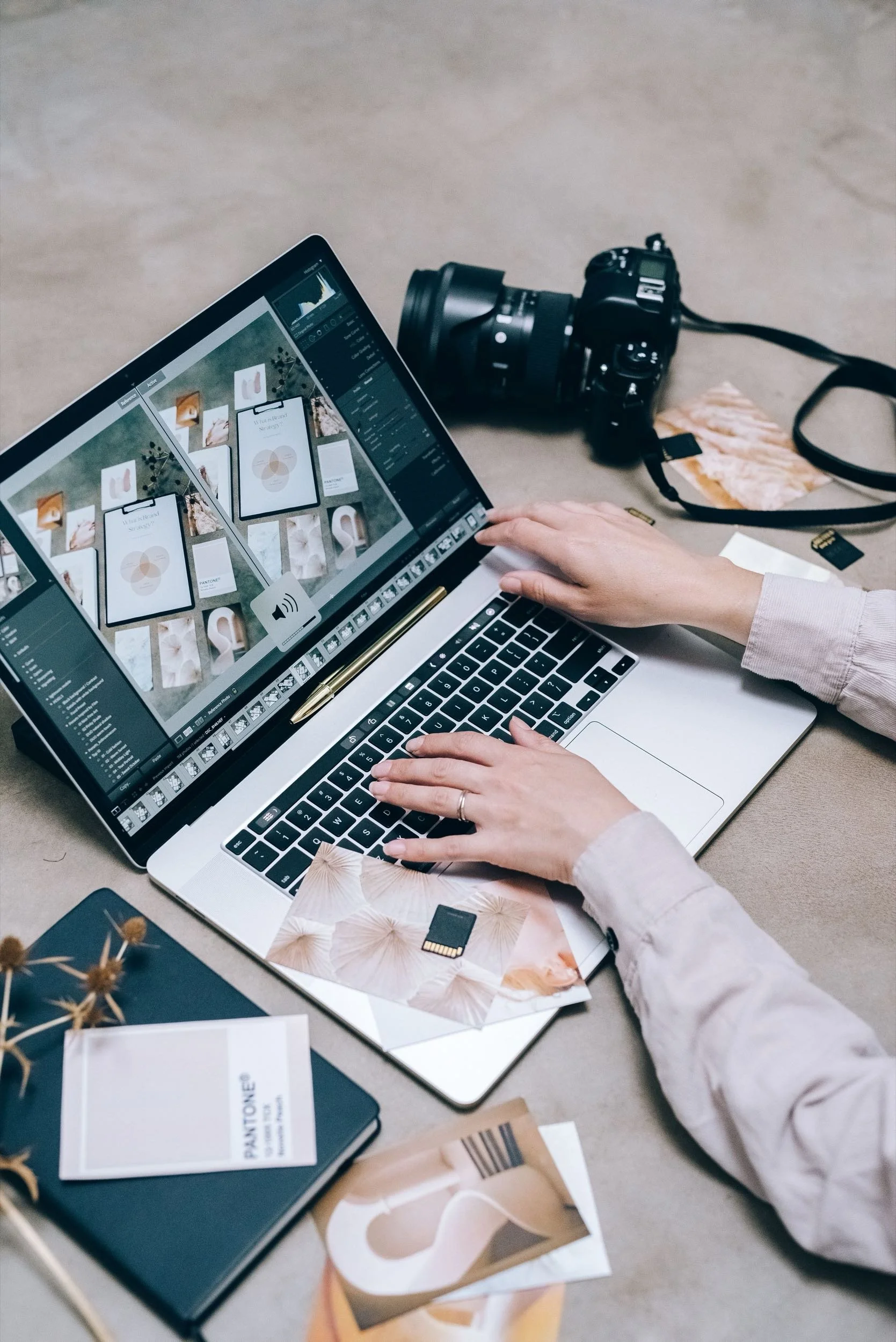 Woman editing photos on a laptop beside camera