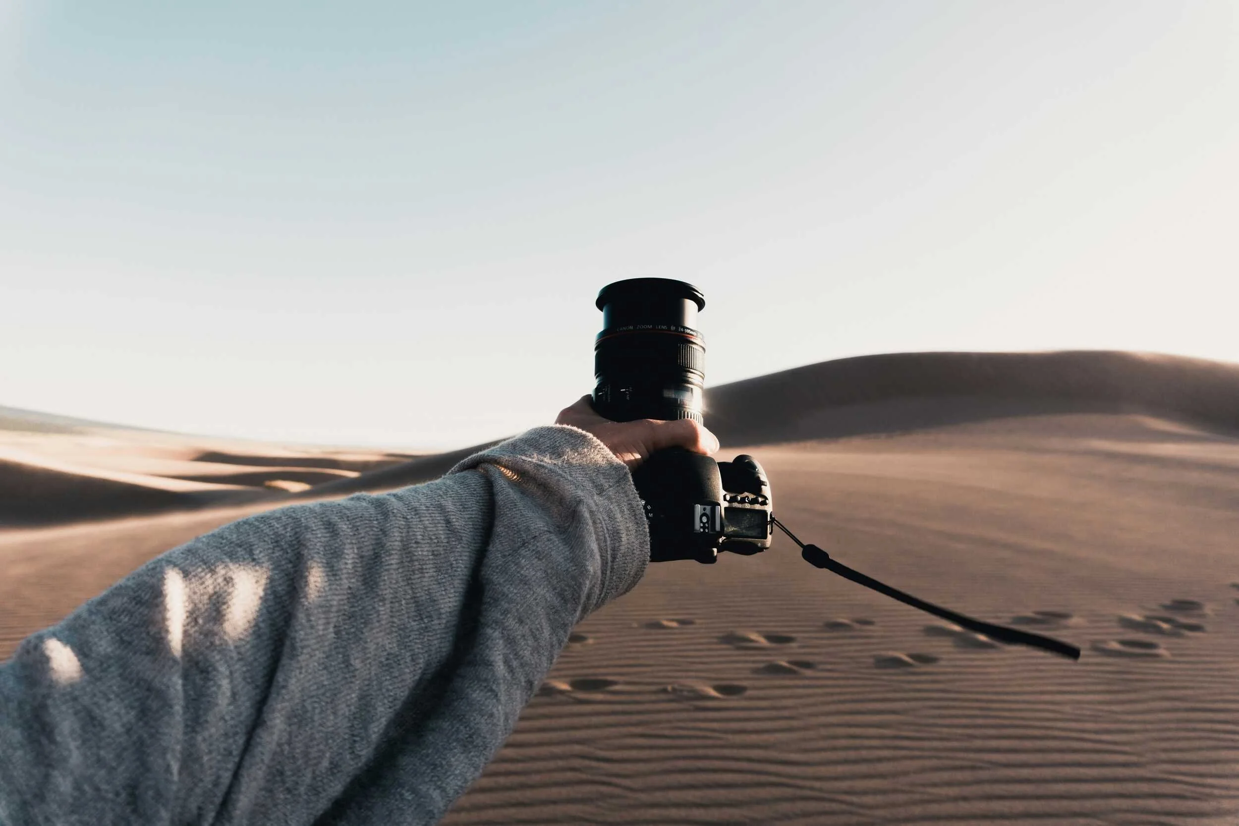 Man carries camera in desert