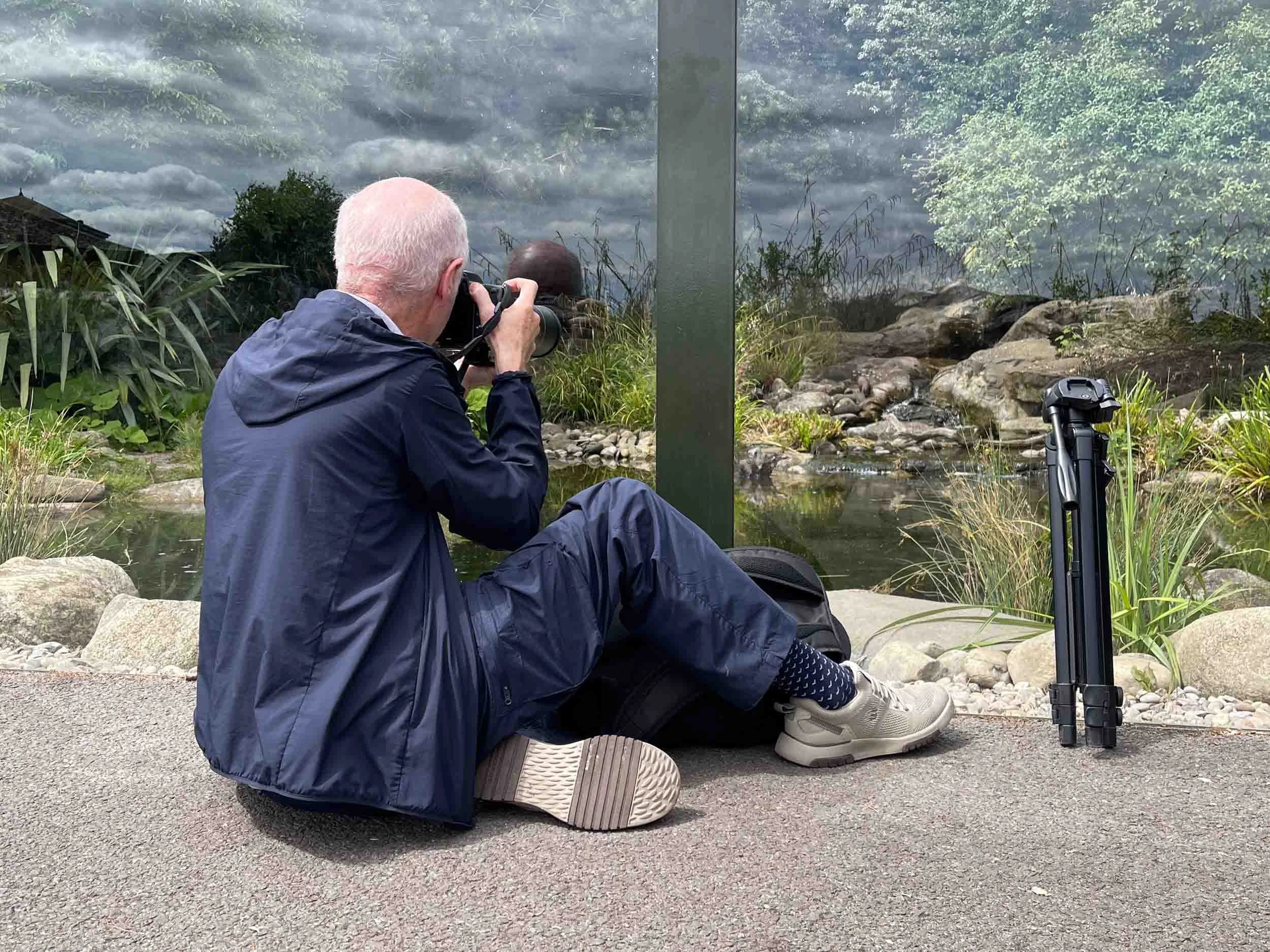 Man sits photographing otter through glass.jpg