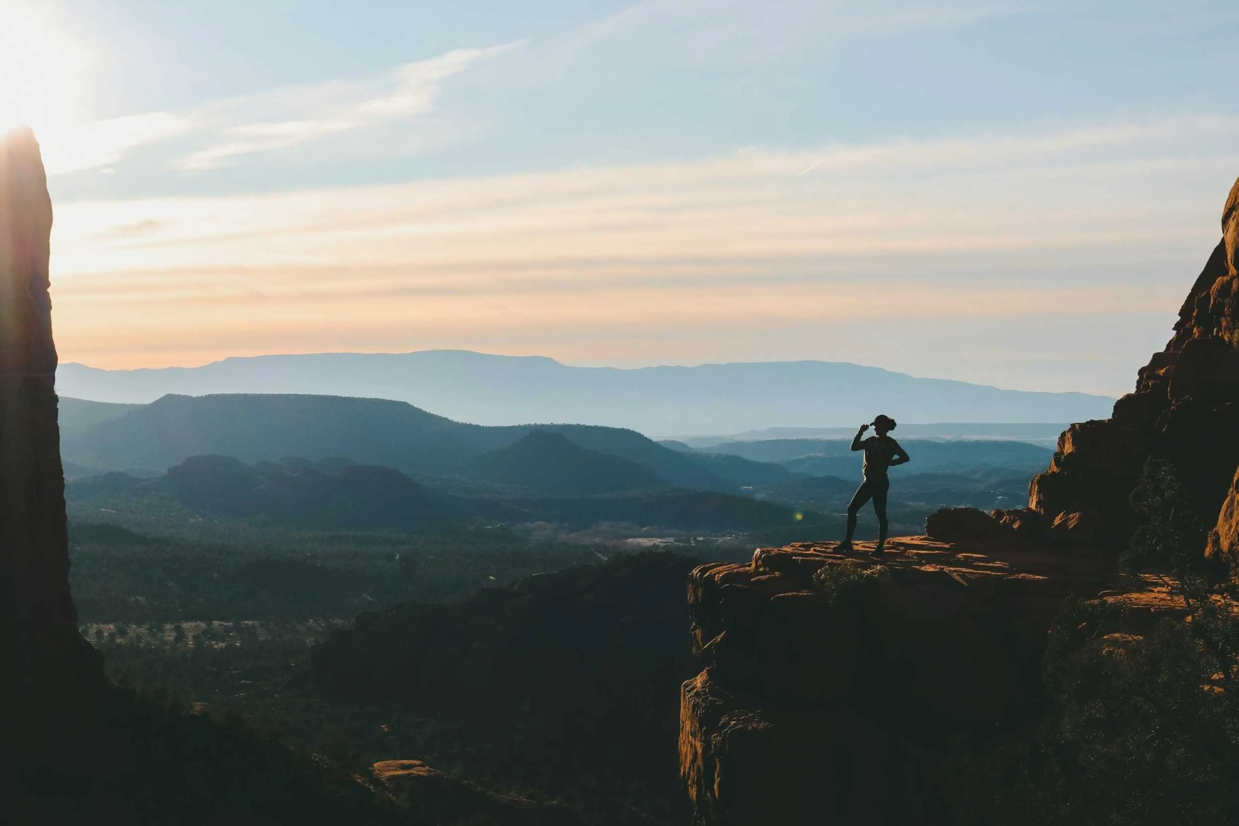 Woman stands admiring view from cliff