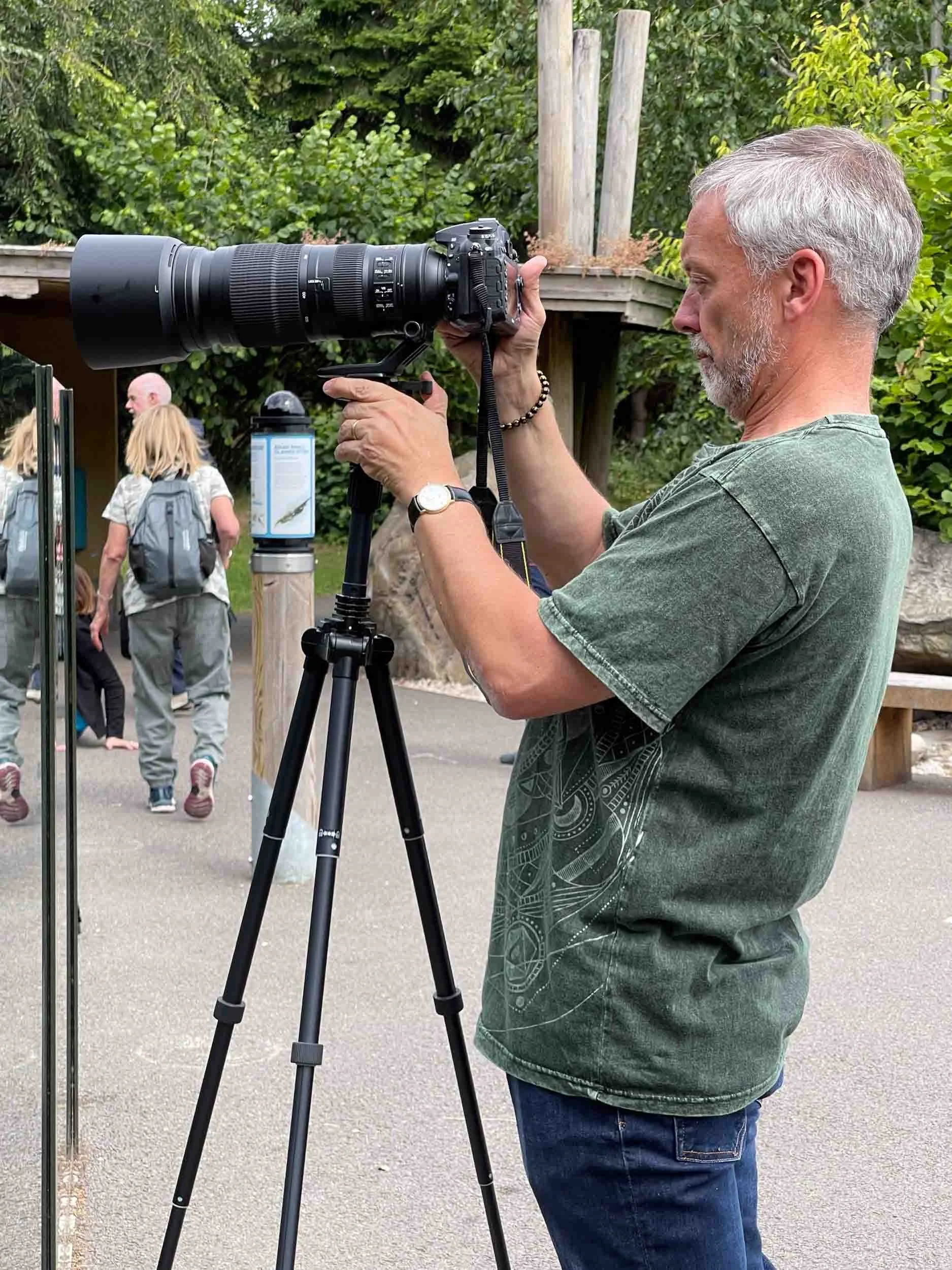 Man stands adjusting camera on tripod.jpg