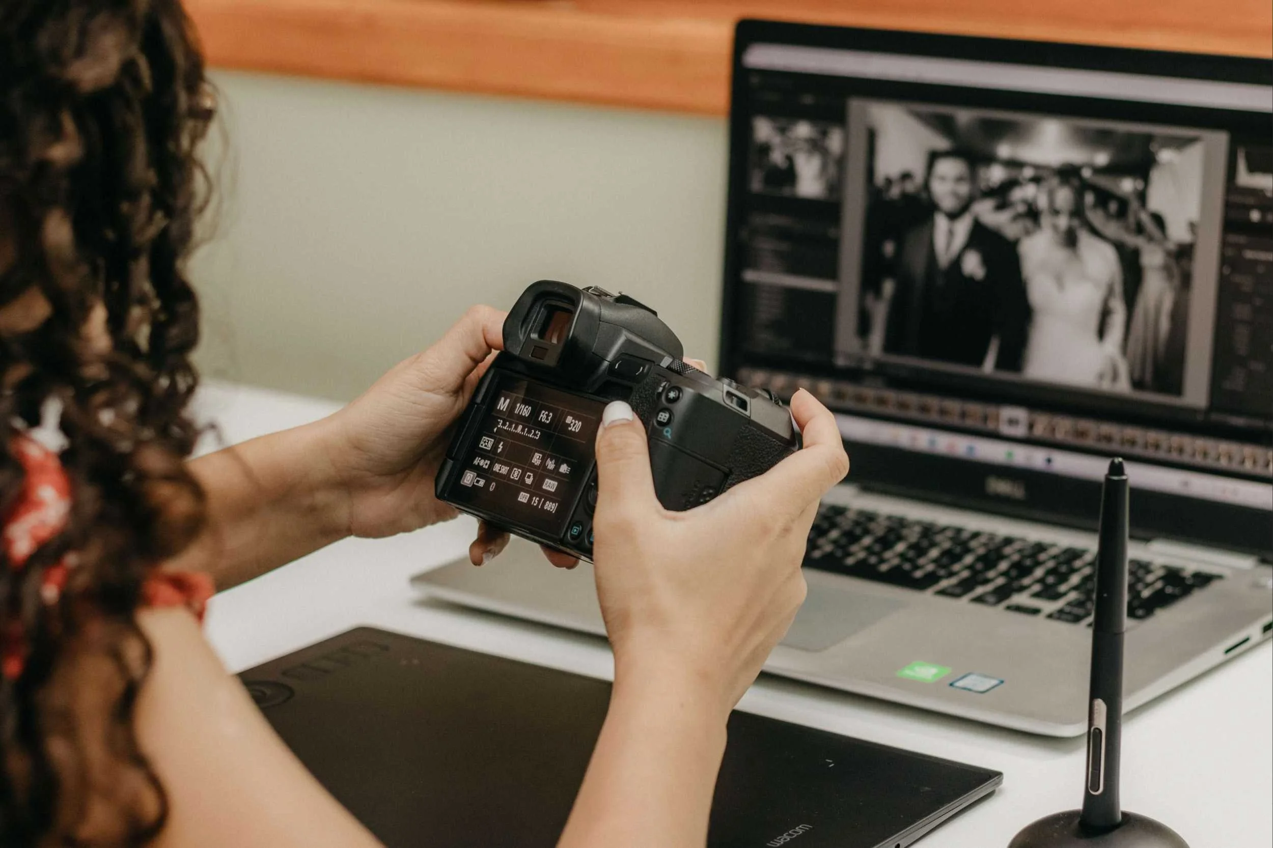 Woman holding camera in front of laptop