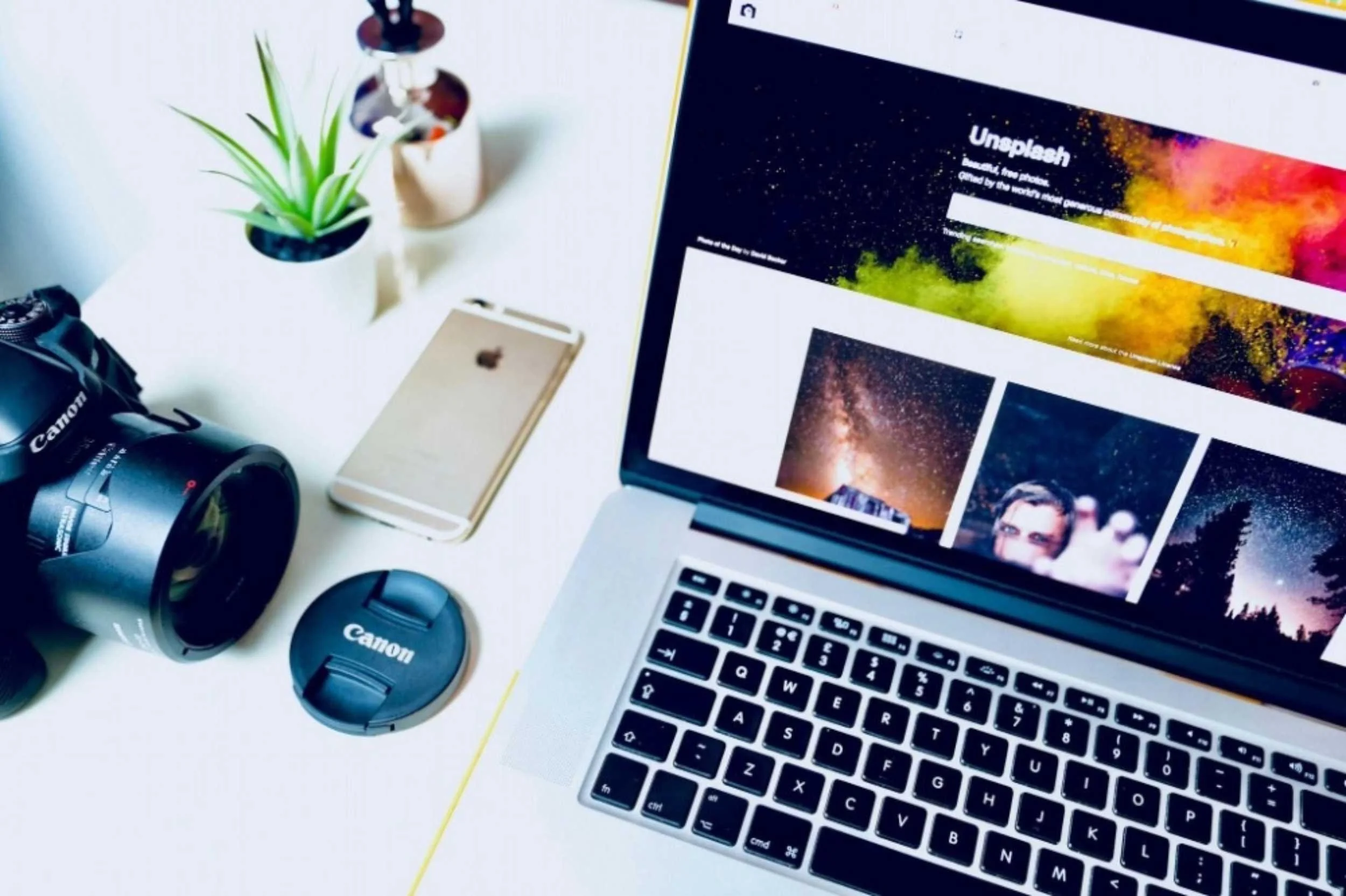 Camera, phone, laptop and plant on desk