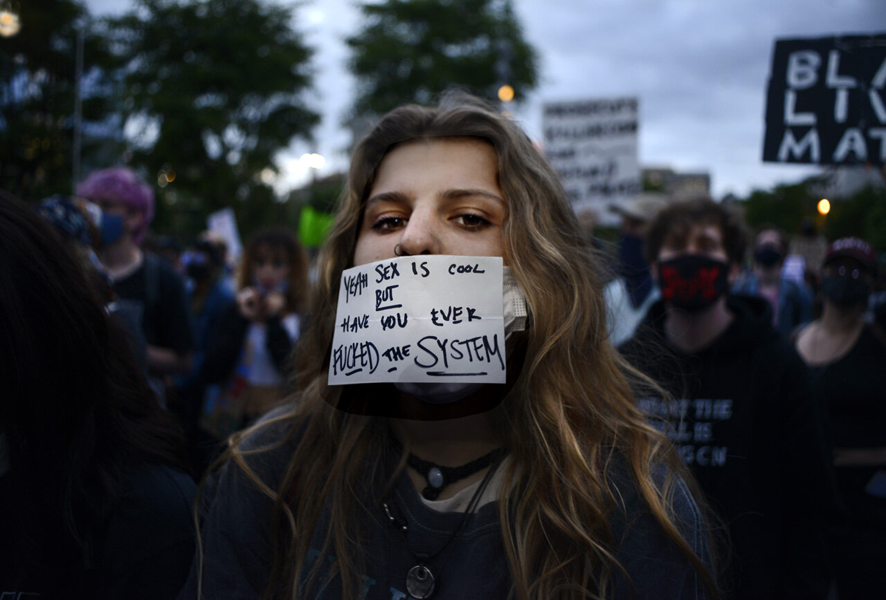  GEORGE FLOYD PROTESTS Wearing a Covid19 mask fashioned into a mini protest sign, a young woman marches in a mass demonstration in downtown Los Angeles 