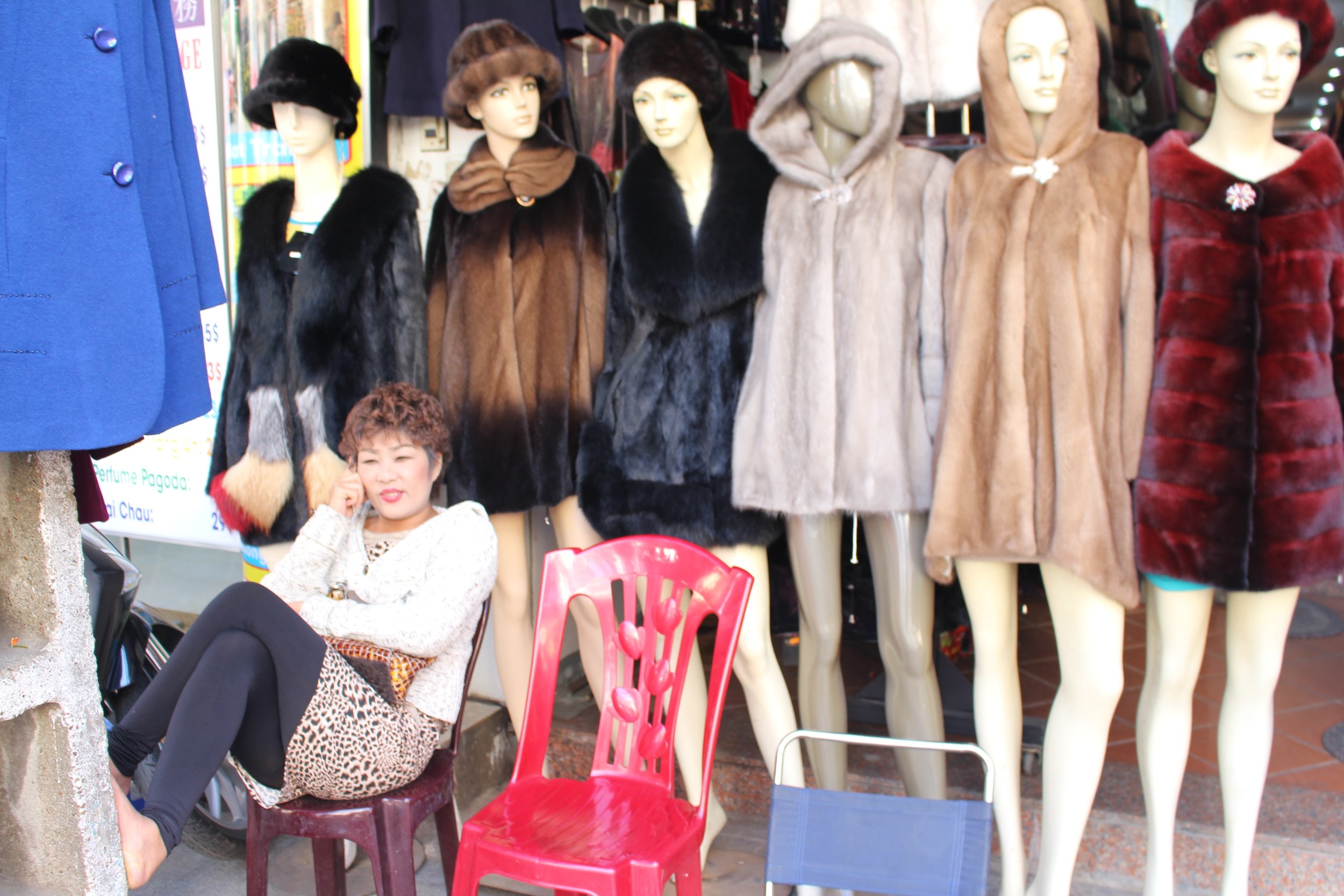 A coat seller talks on her phone, Hanoi