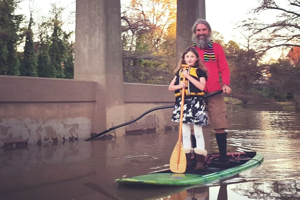 John Ruskey pilots a SUP with a young protégé.