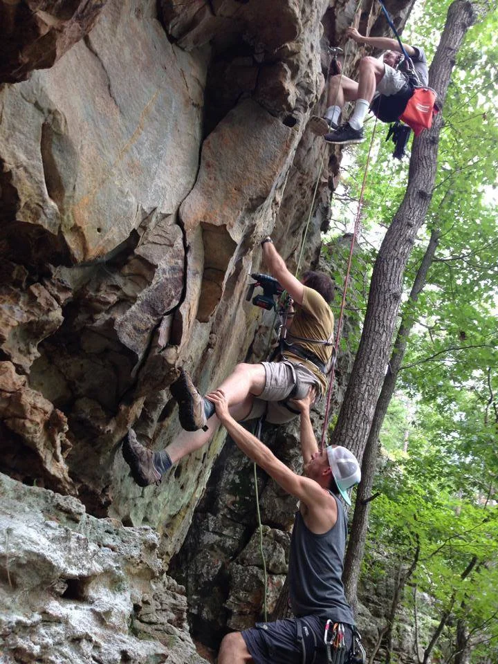 Here, Kyle supports Aaron as he drills holes for a route at Jamestown Crag. Nathan, the eldest of the three brothers, works above.
