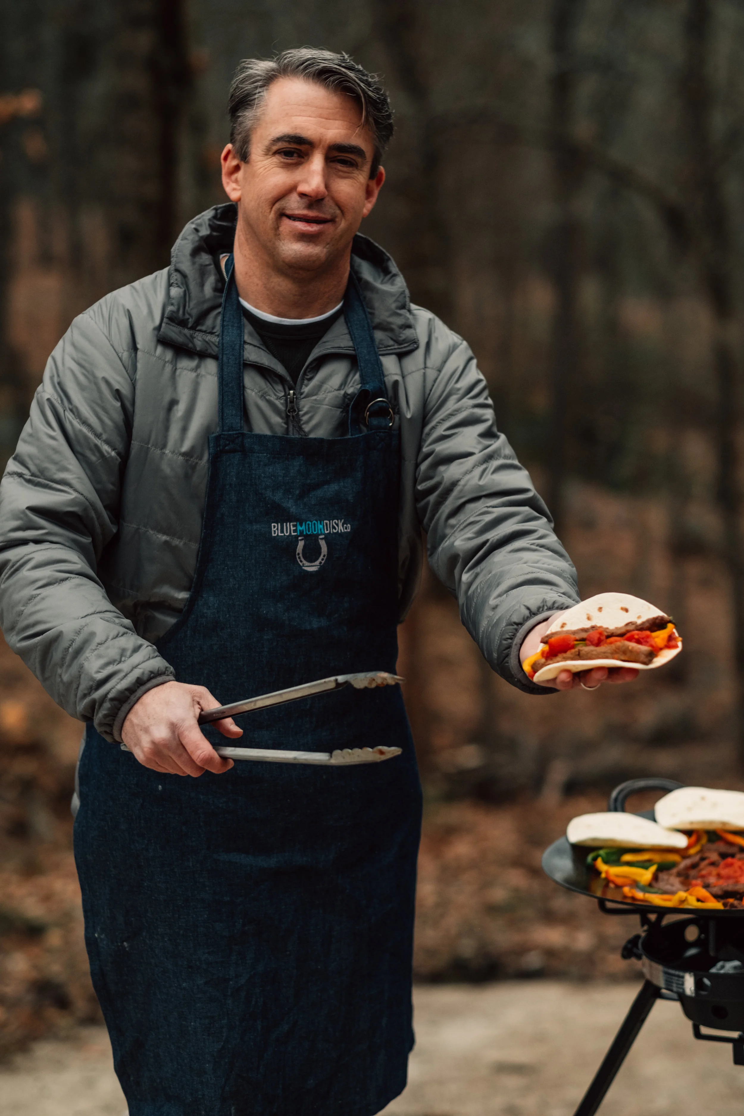 Chuck Peyton, owner and inventor of the Blue Moon Disk, sprinkles Discada Seasoning over deer-steak fajitas during a backyard cookout. The all-purpose seasoning includes a custom blend of spices that brings out the savory flavor of any dish.