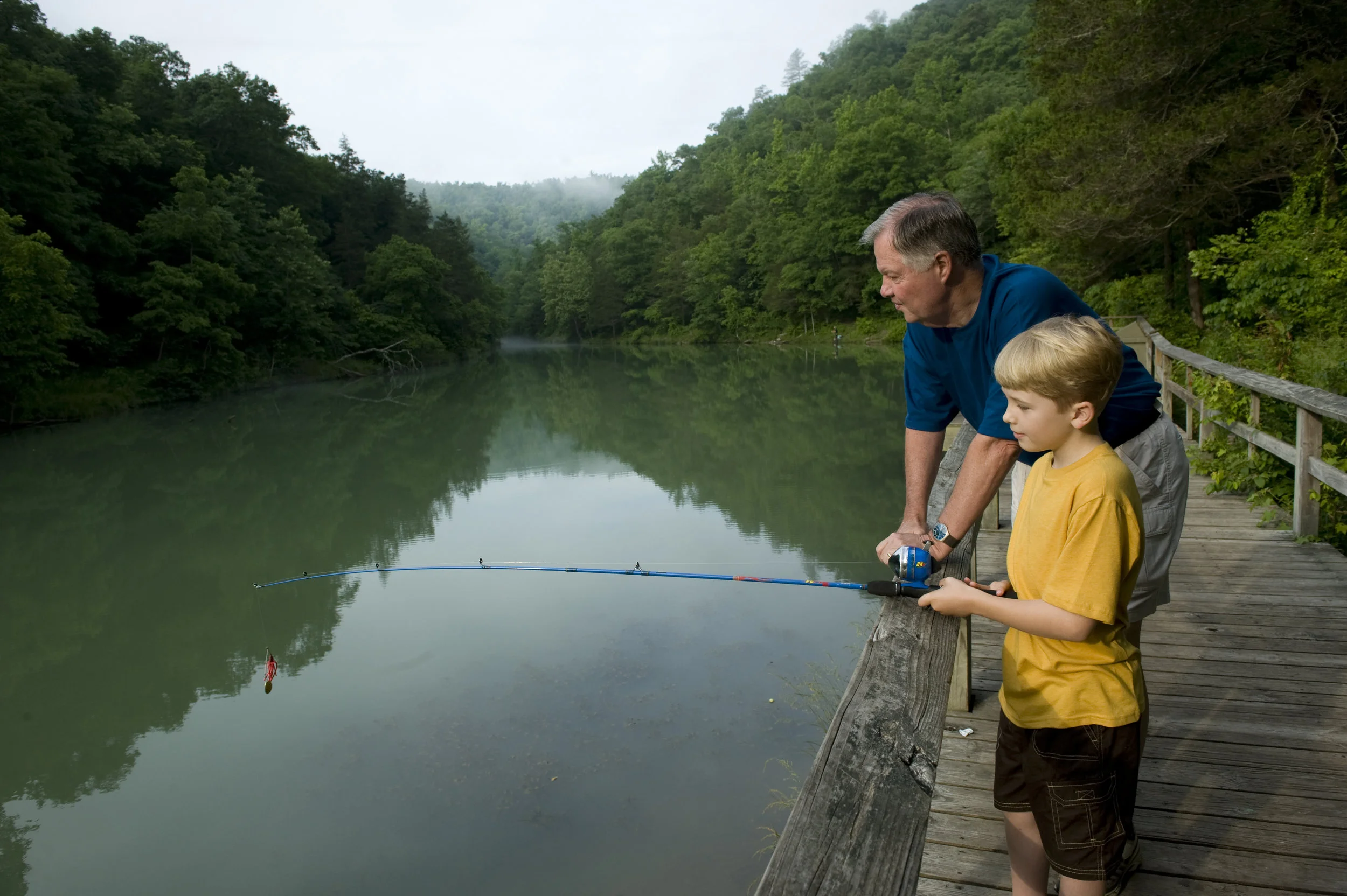 A grandfather teaches his grandson about the joys of fishing.