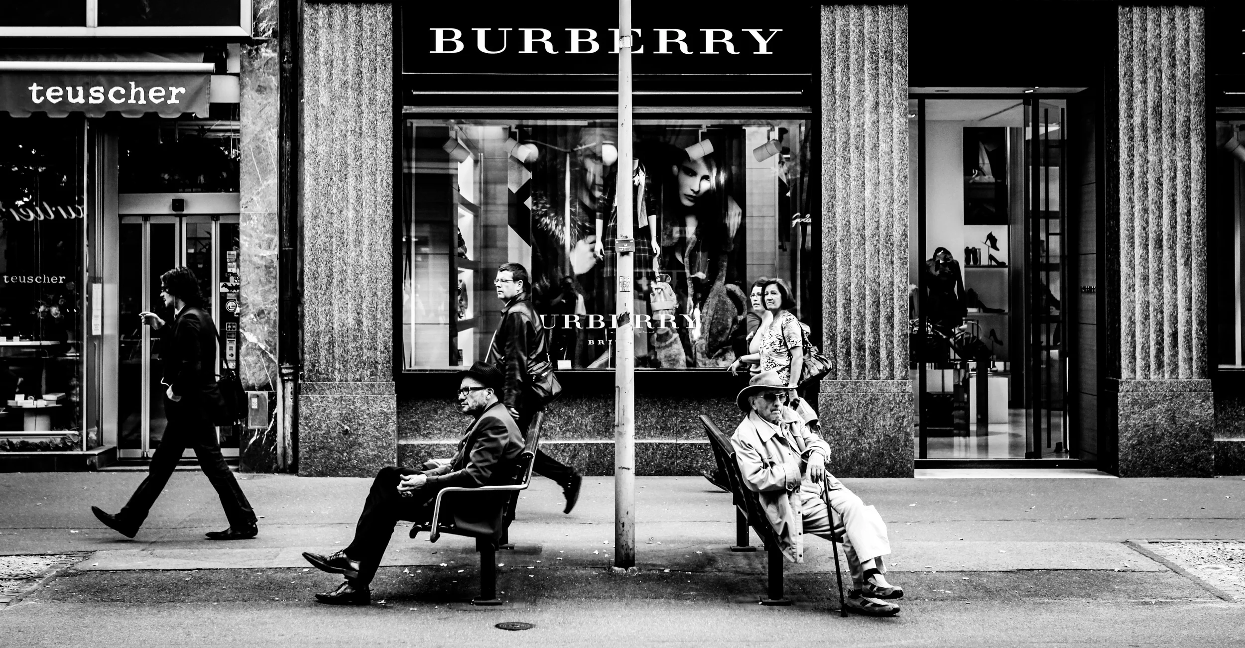 Two Men sitting on a street in front of Burberry
