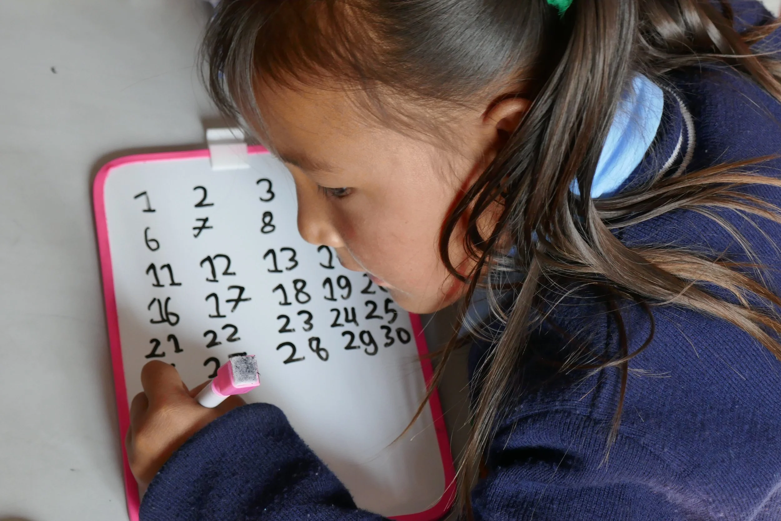 A kindergarten student in Melamchi Ghyang School in Nepal writing her numbers to 100