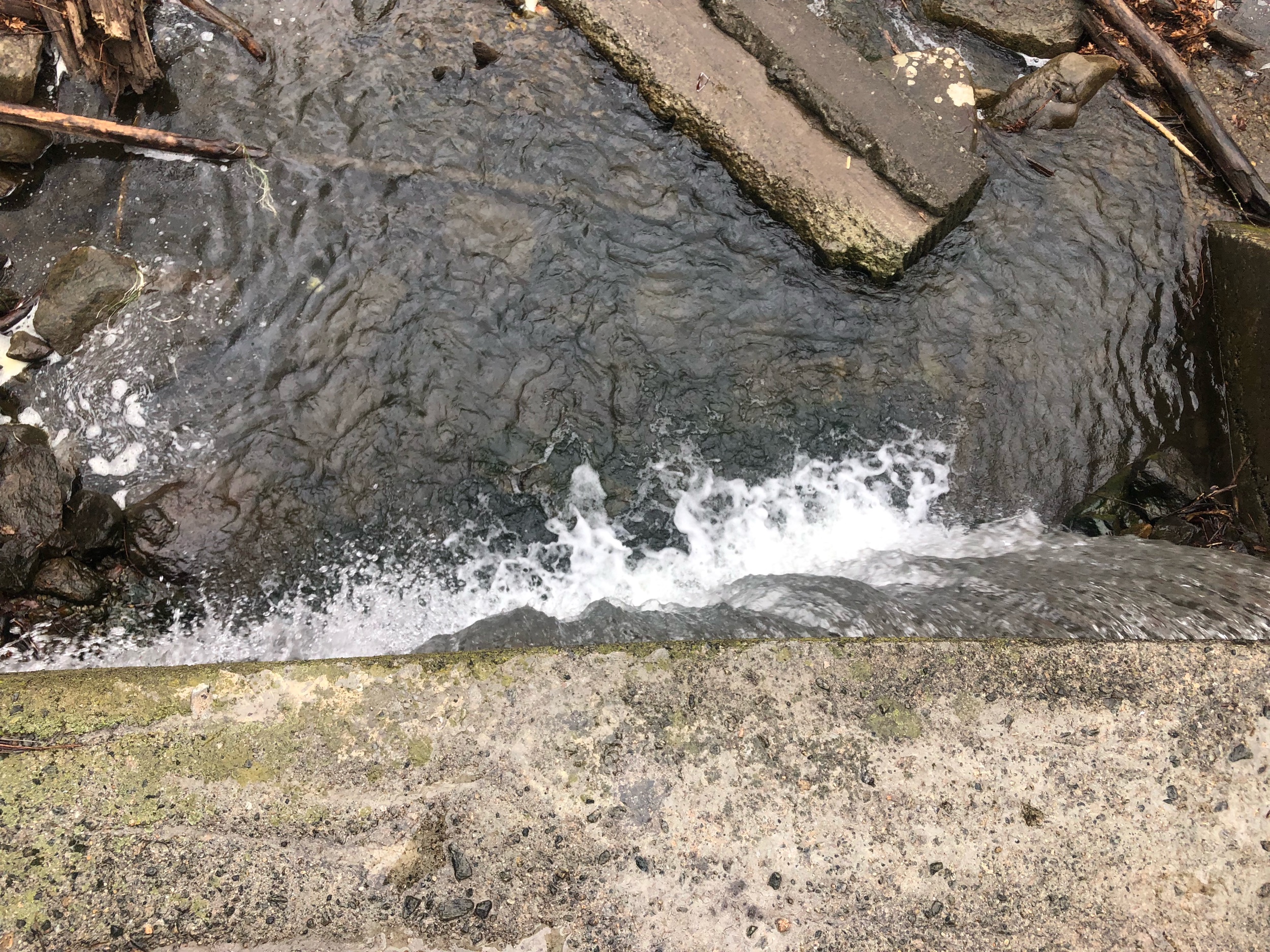 Above the concrete waterfall- model laying along edge- drone shot from above