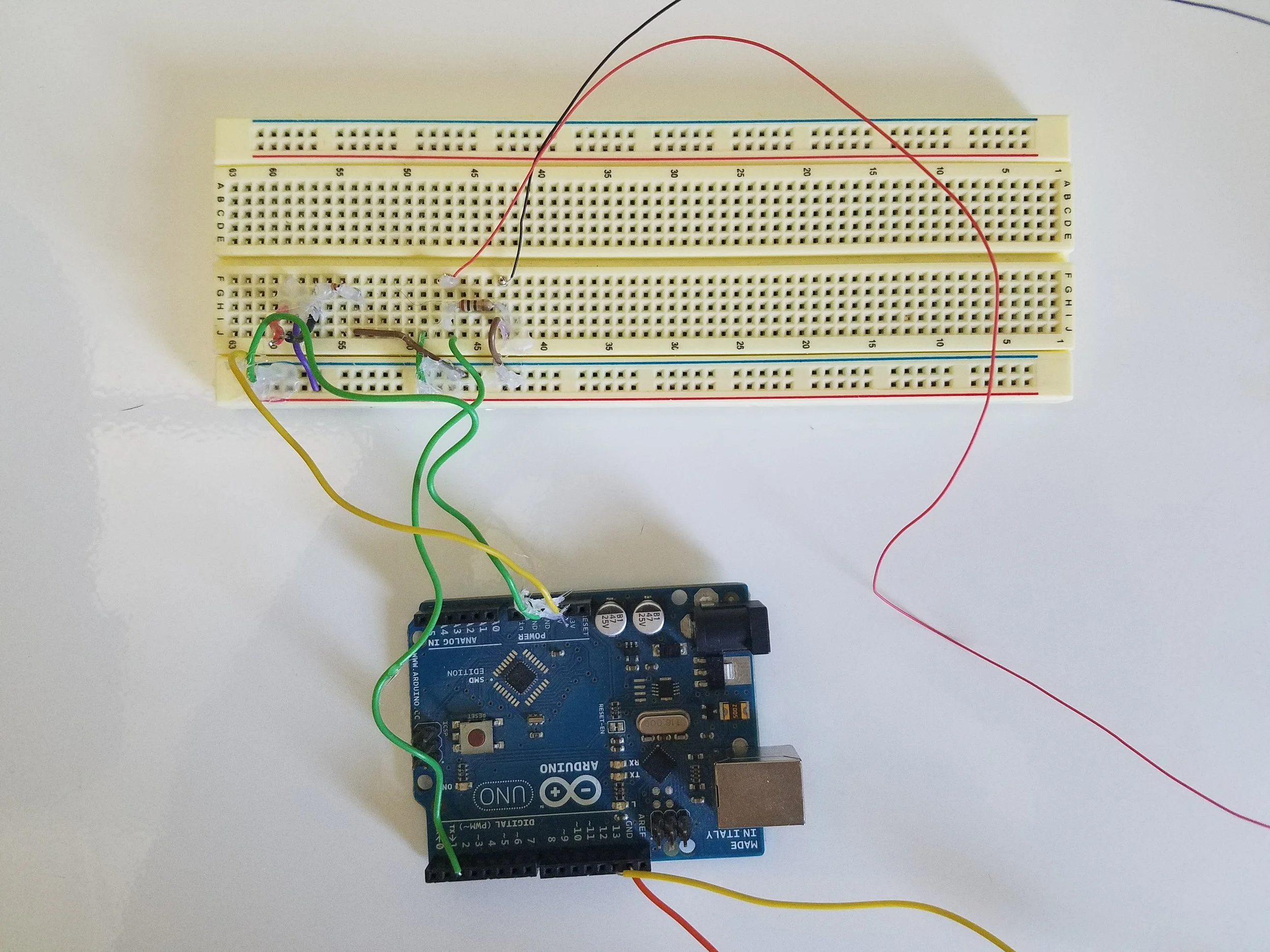 Hot glue holds the leads of the wires. The custom circuit and the push button inside the bottle are connected.