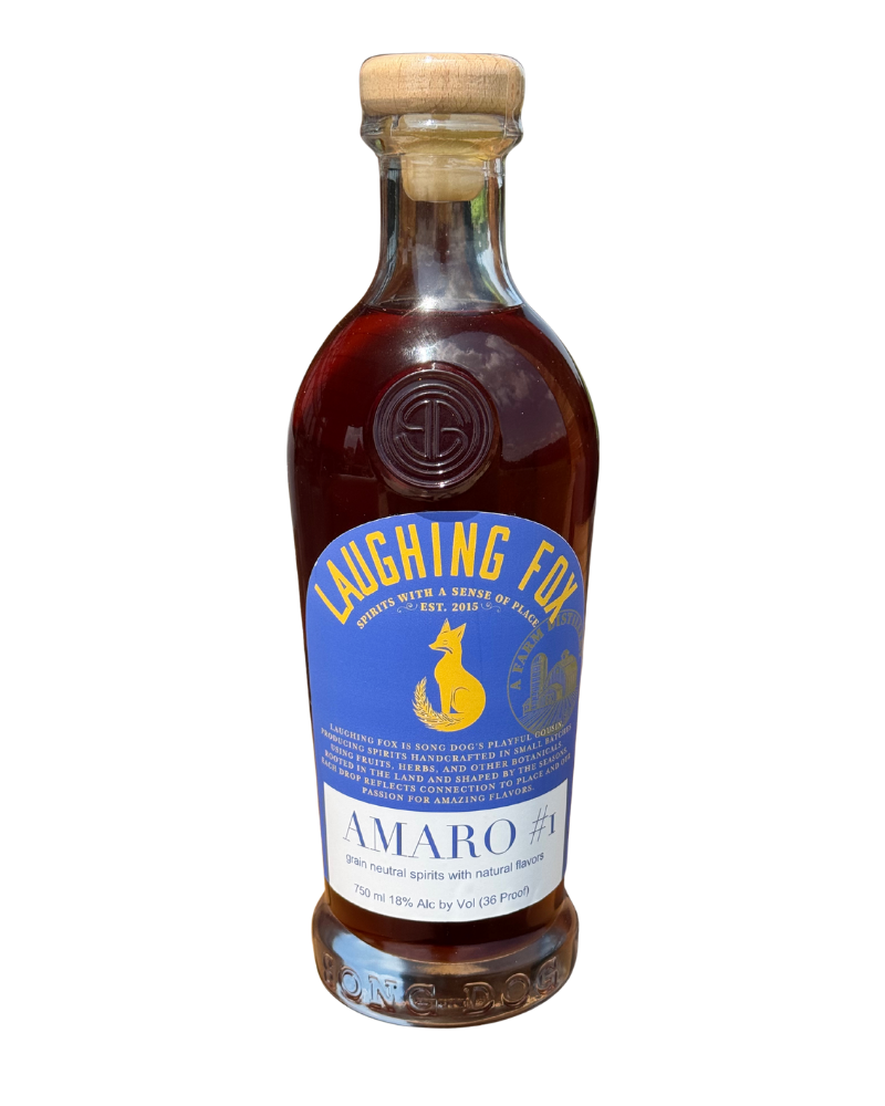 A 750ml clear glass bottle of Laughing Fox Amaro, with a wooden cork, containing a dark brown liquor. The label features a yellow fox silhouette, blue background, and yellow and white text, indicating it is grain neutral spirits with natural flavors, 18% alcohol by volume.