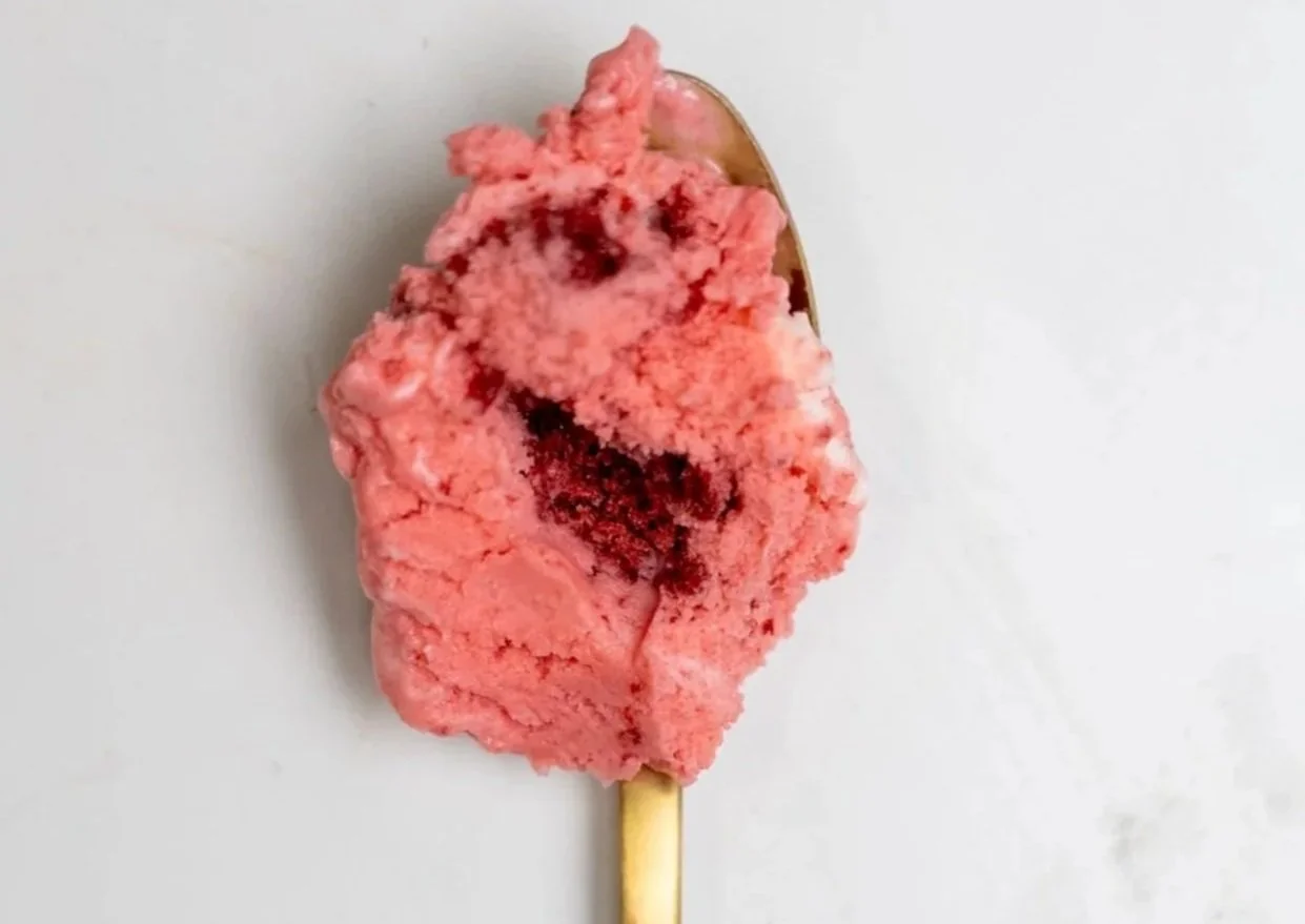 A scoop of red velvet cake ice cream on a golden spoon