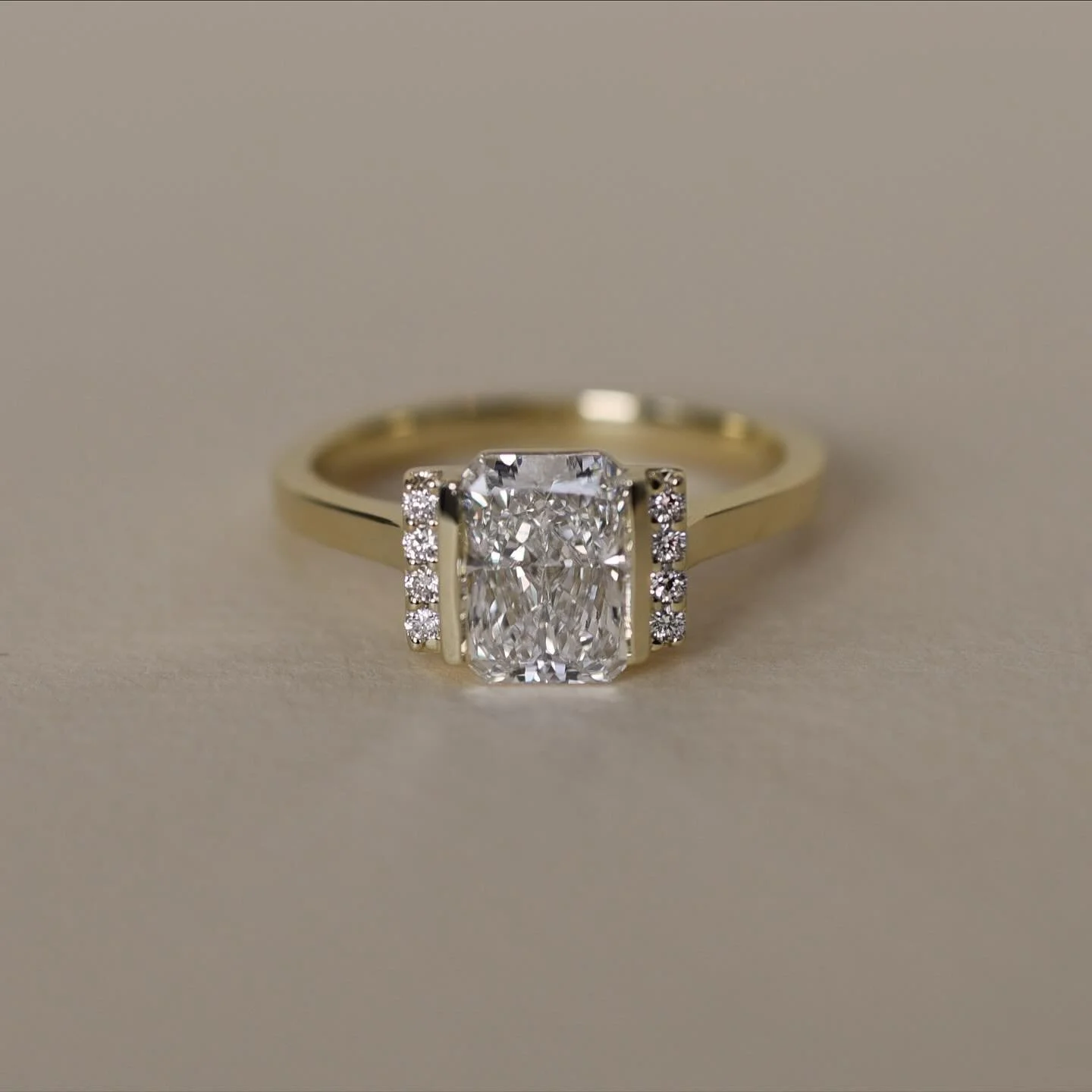 This special engagement ring was inspired by our Estella Ring. We made it unique by changing the prongs to bars, adding an extra round diamond on each side, and adjusting the setting so it can stack flush with a straight wedding band. Thanks so much 