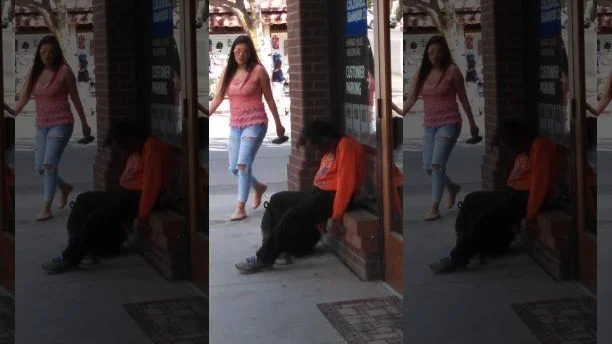 A panhandler sleeps in front of a business