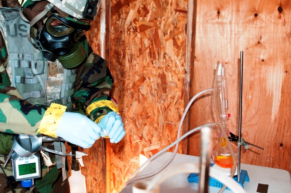 Warrant Officer Christopher Dawson, 9th Chemical Company, gathers simulation samples during training from a site set up as a suspected chemical weapons lab. Operation Rolling Thunder, Oct. 15-17, provided the 110th Chemical Battalion an experience for soldiers trained in tech escort missions to put their sample-gathering skills to the test. Photo by SGT Mark Miranda, 5th Mobile Public Affairs Detachment. Public Domain.