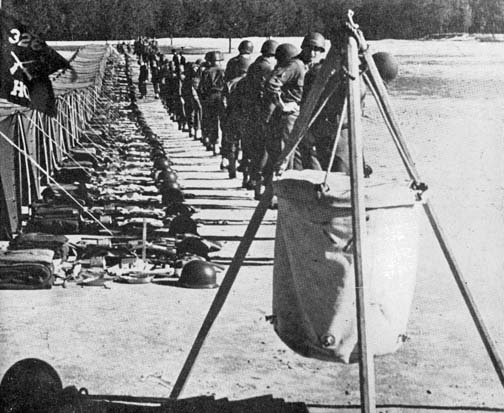 A Lyster Bag, similar to those from the First World War, hangs in the foreground of an American encampment in World War II. (Source: Public Domain)