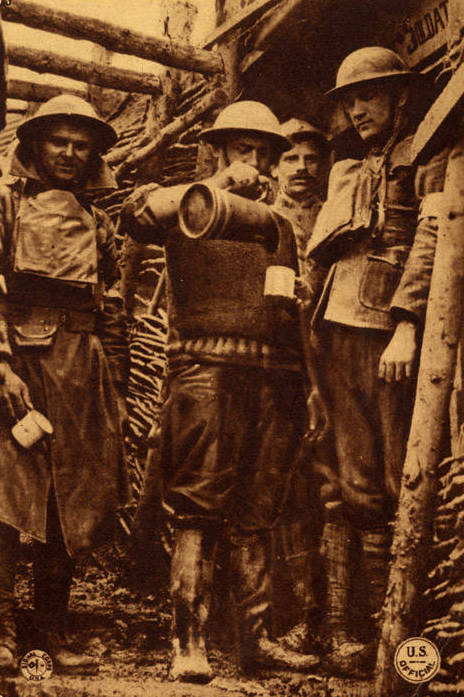 A "Y" Man of the YMCA pours coffee for American troops on the line as a French Poilu looks on