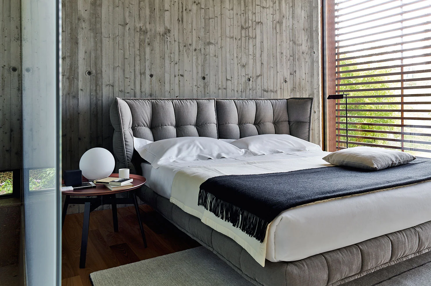 B&B Italia's Husk bed is a soft touch against this concrete wall. Instead of a conventional bedside table, beside the bed is the Husk side table .
