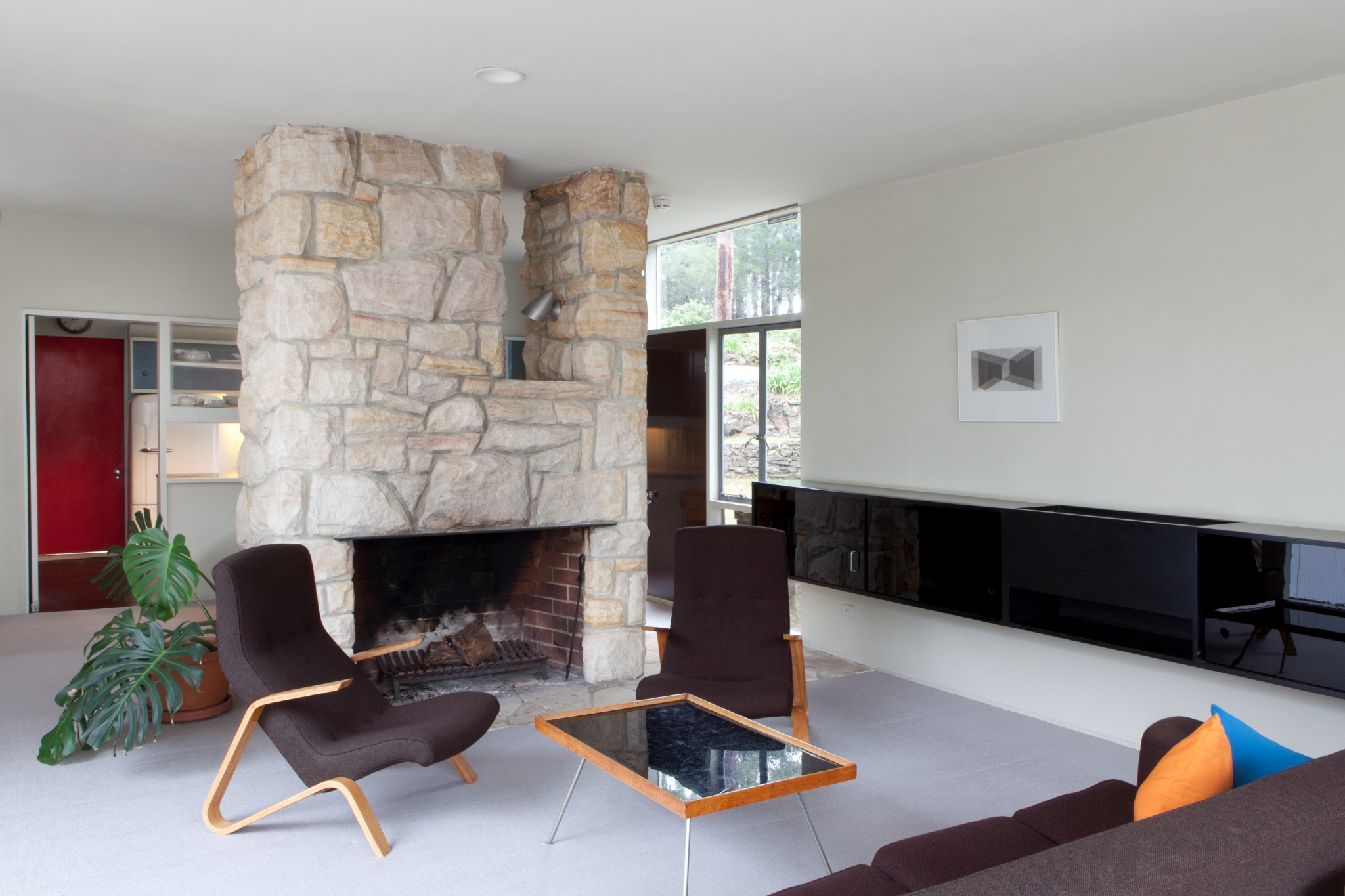 The open plan lounge room featuring the central fireplace and dining area behind. Photograph copyright Jamie North for Sydney Living Museums. 