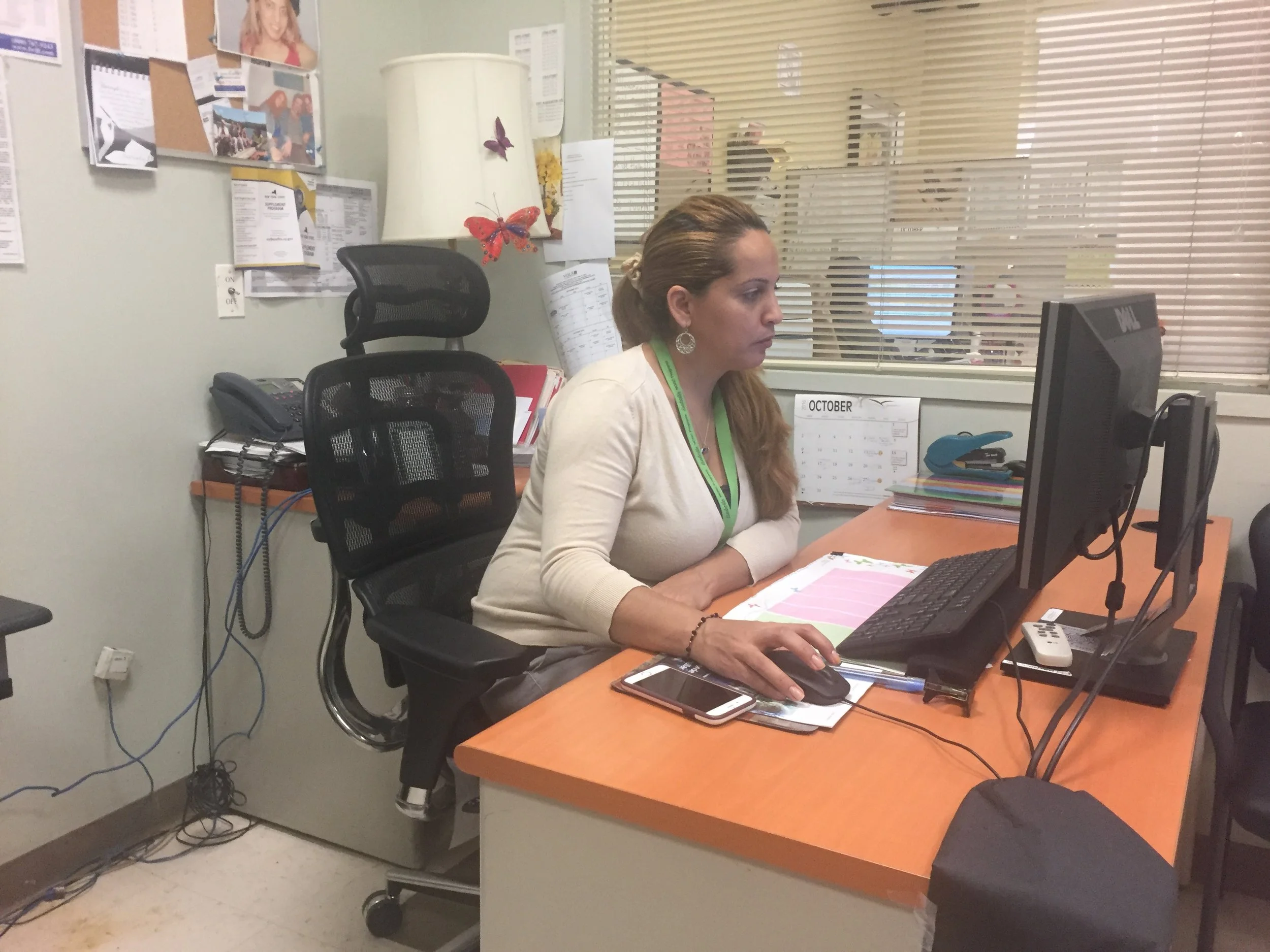 Millie Almonte, a client services manager at Isabella Senior Center, works at her desk. A rainy Friday afternoon brings in few NORC residents looking for senior services (Photo: Emily Dugdale).