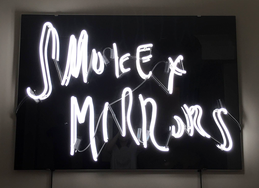 Neon white sign on a black background with a black mirror floor by