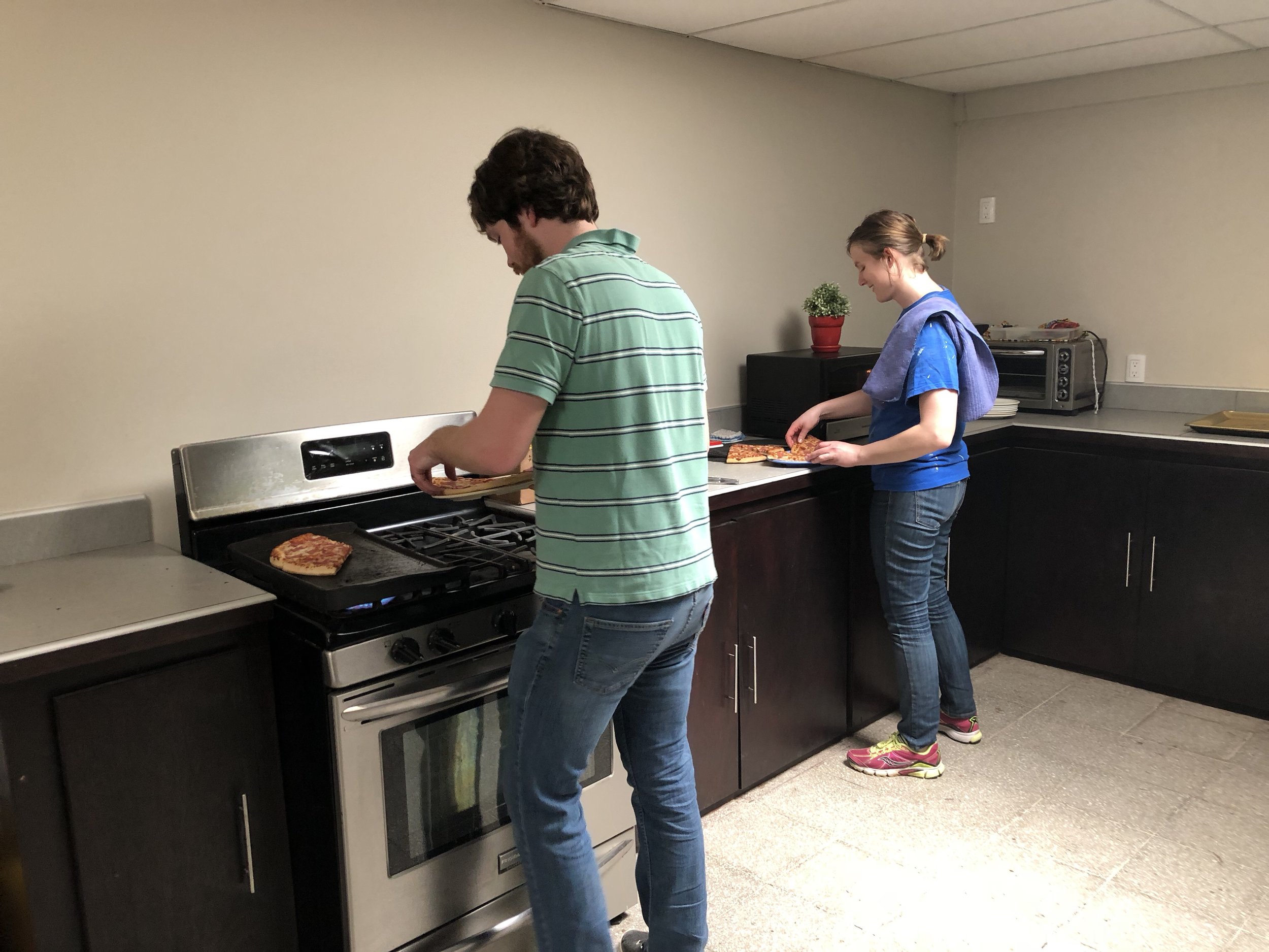 Eric and Rachel warming up pizza for clients of the El Faro program.