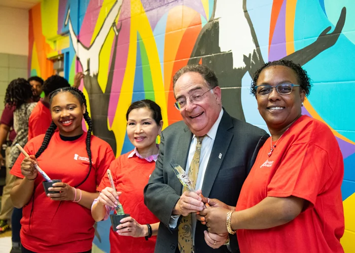 Taking a break from painting, (from left) Dyelle Washington, a sophomore at Renaissance Academy, MD First Lady Yumi Hogan, UMB President Jay A. Perman, MD, and Renaissance Academy Principal Tammatha Woodhouse, pose for a picture in front of the colorful mural.