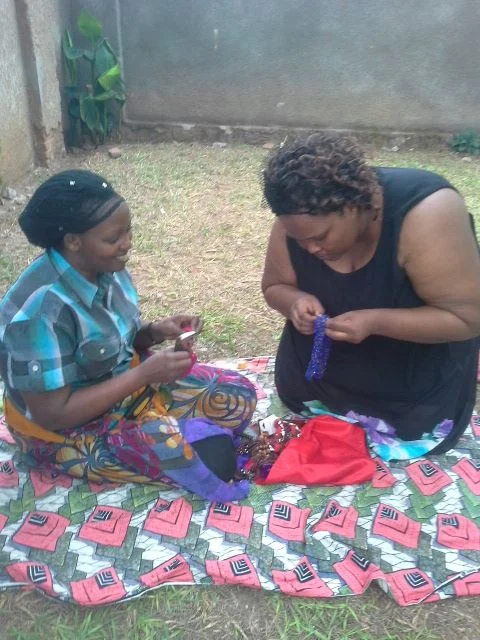 Women in Burundi making beaded necklaces