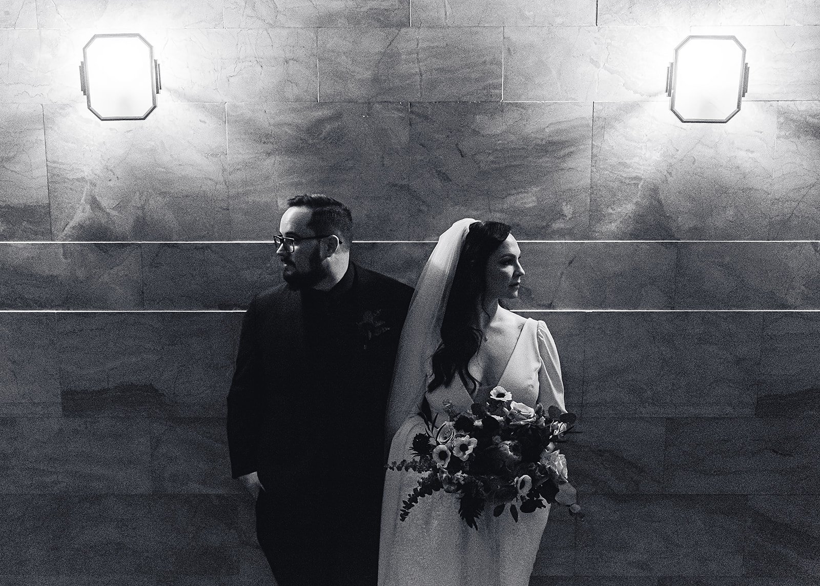  a stoic black and white image of a bride and groom looking in opposite directions on their wedding day 