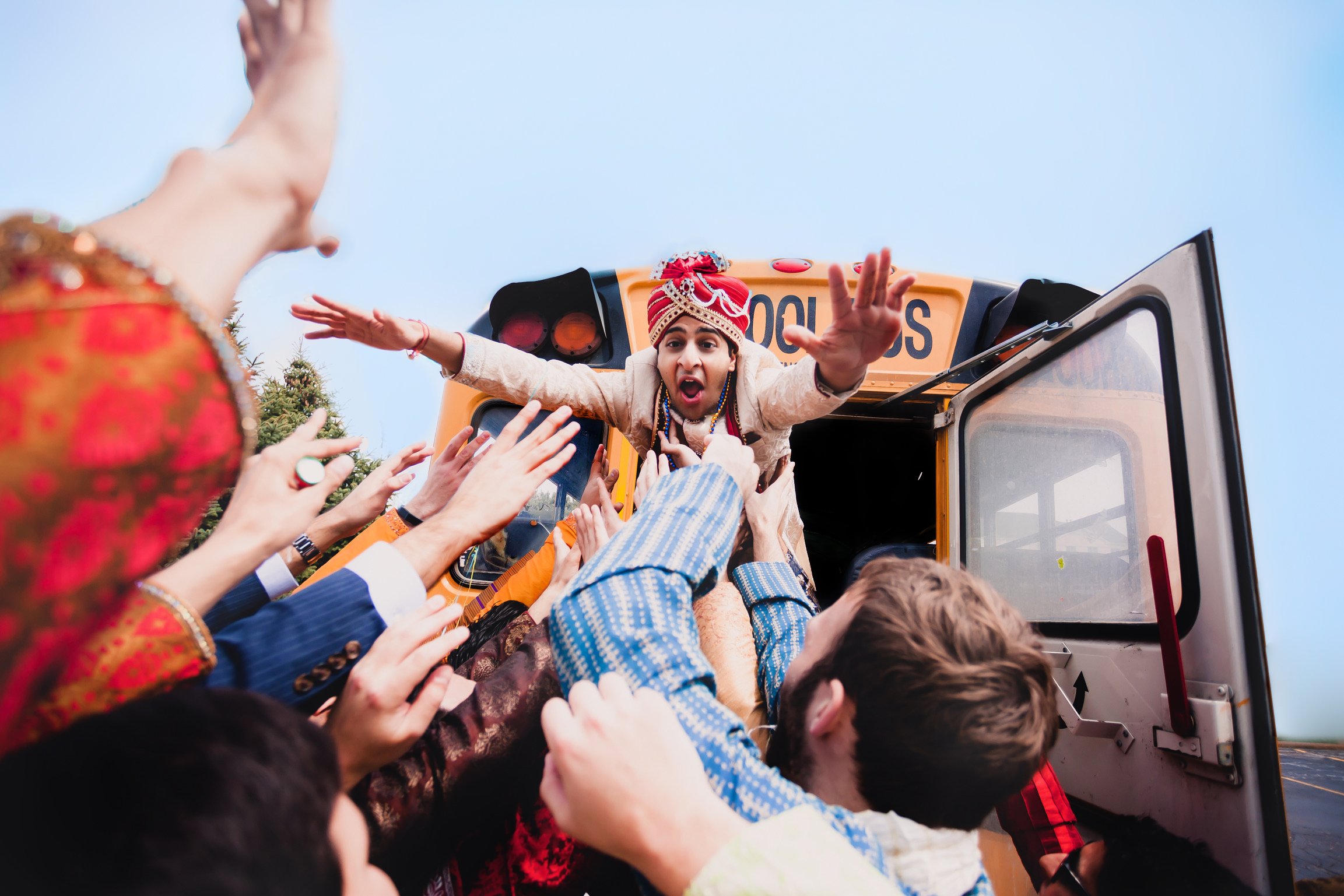  An Indian groom jumps out of a schoolbus and into the arms of his friends and family. South Asian Wedding 